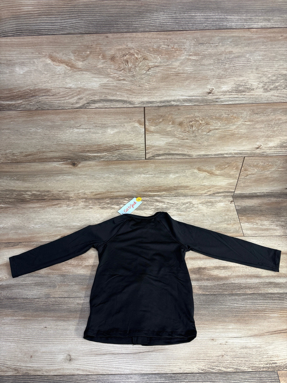 Black long-sleeve shirt with Cat & Jack tag laid flat on wooden floor