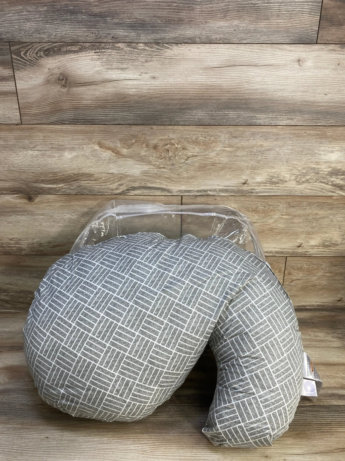 Front view of Boppy Cuddle pregnancy pillow in grey basket weave slipcover in original packaging on wood plank floor