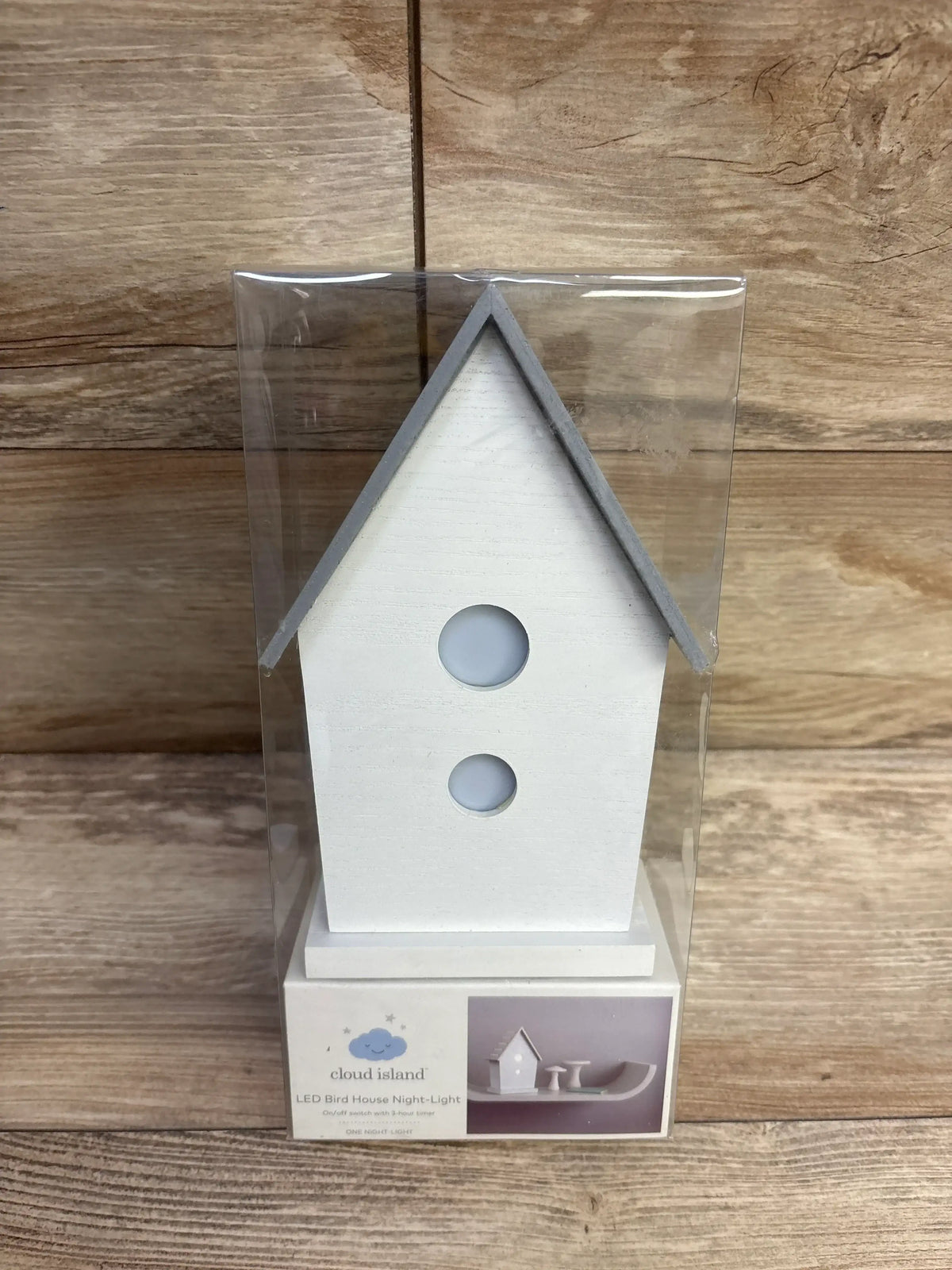White LED birdhouse night light in packaging, wooden background, nursery decor