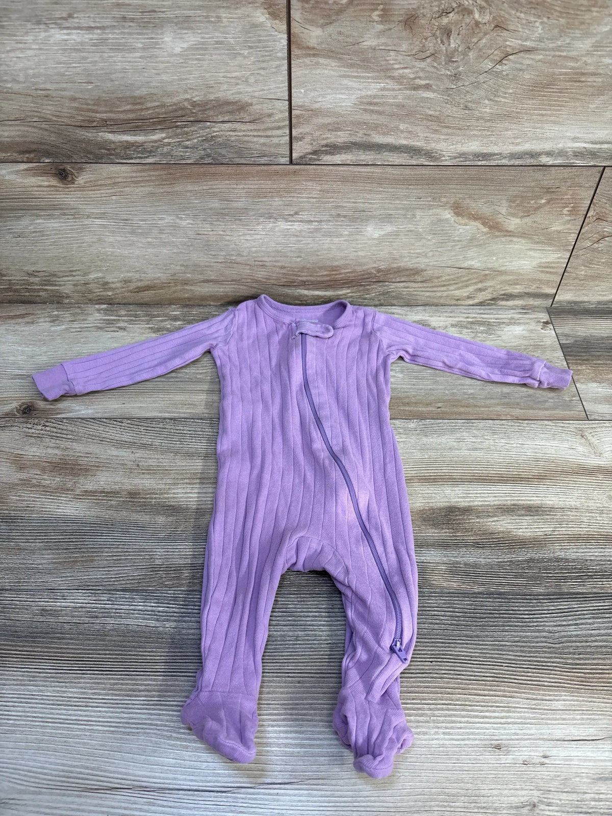 Front view of Member’s Mark purple ribbed sleeper showcasing ribbed fabric, long sleeves, and diagonal zipper on wood-look flooring