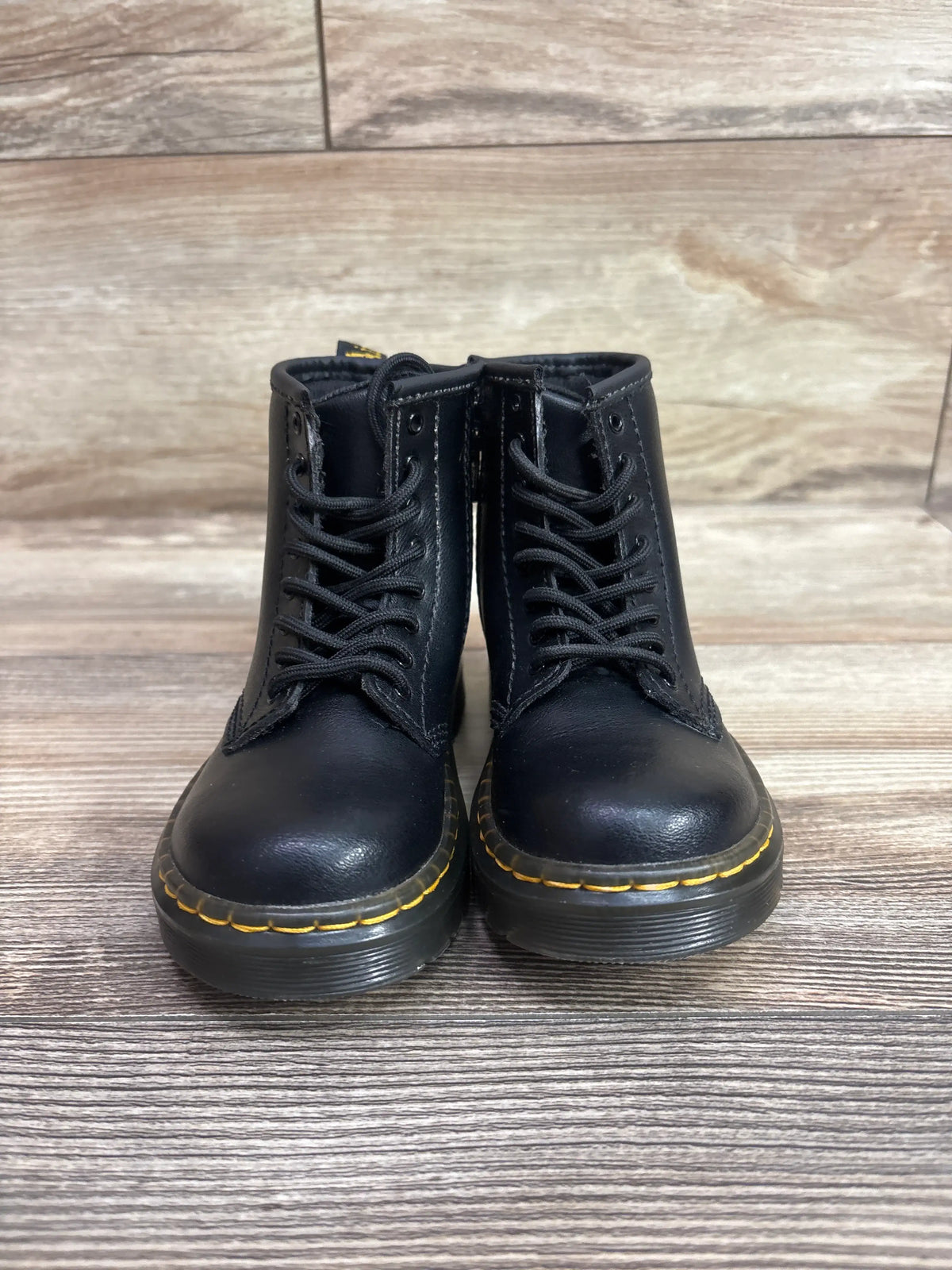 Pair of black Me n Mommy To Be leather lace-up boots with yellow stitching on wood background