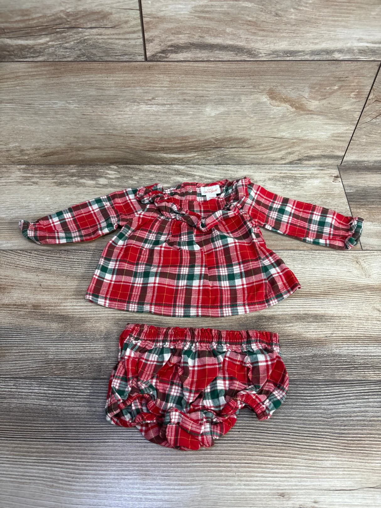 Red, green, and white plaid long-sleeve baby dress with matching bloomers on wood floor