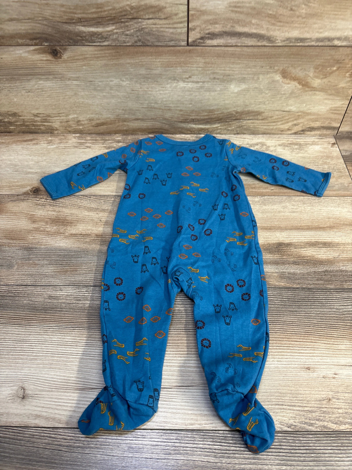 Flat lay of Carter’s blue long-sleeve snap footed sleeper showing animal-print pattern on wood background