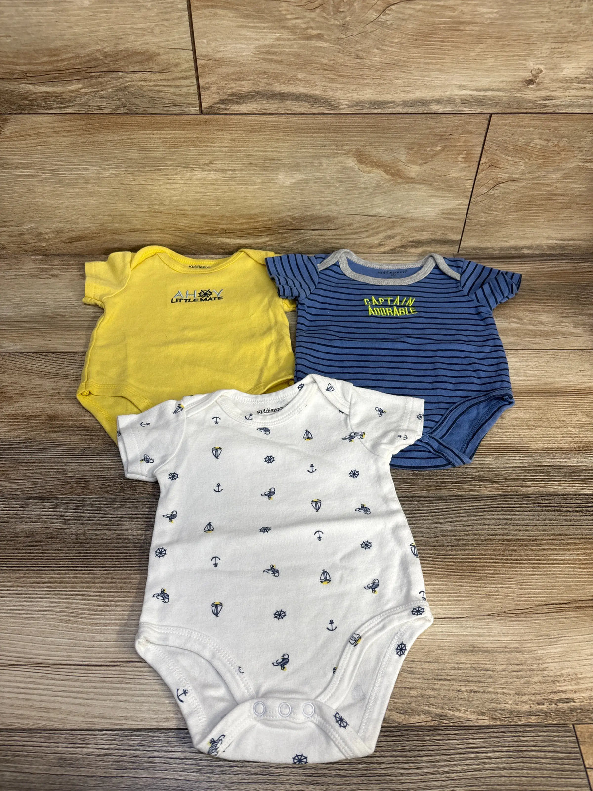 Front view of Kiddiezoon three-piece bodysuit set showcasing yellow, navy stripes, and white nautical prints on a wood floor