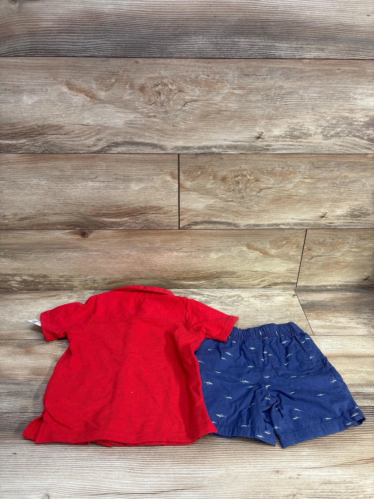 OshKosh 2pc set with red button-up top and blue woven shorts on wood background