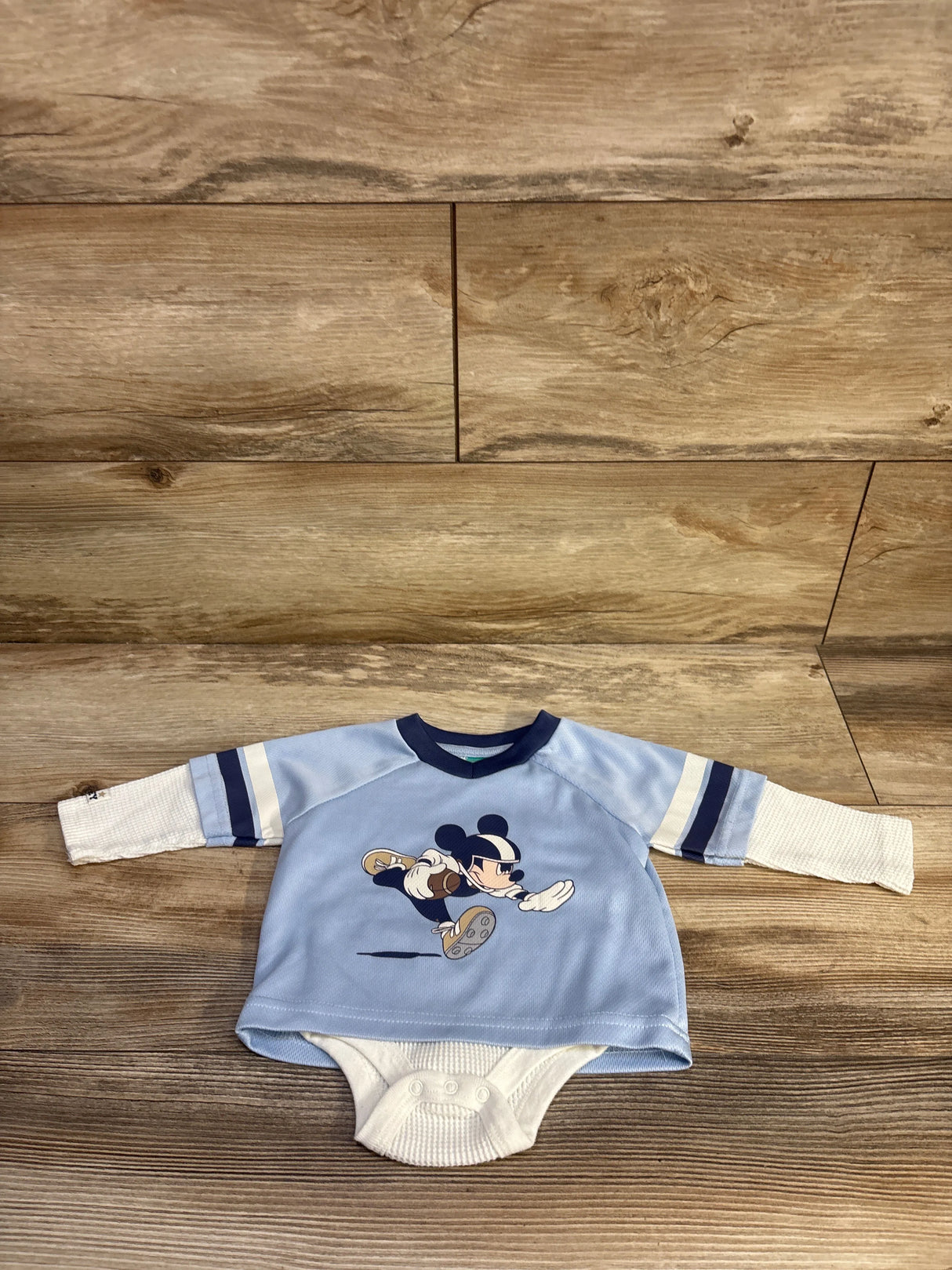 Front view of light blue Mickey Mouse layered bodysuit with navy trim and white waffle-knit snap bottom