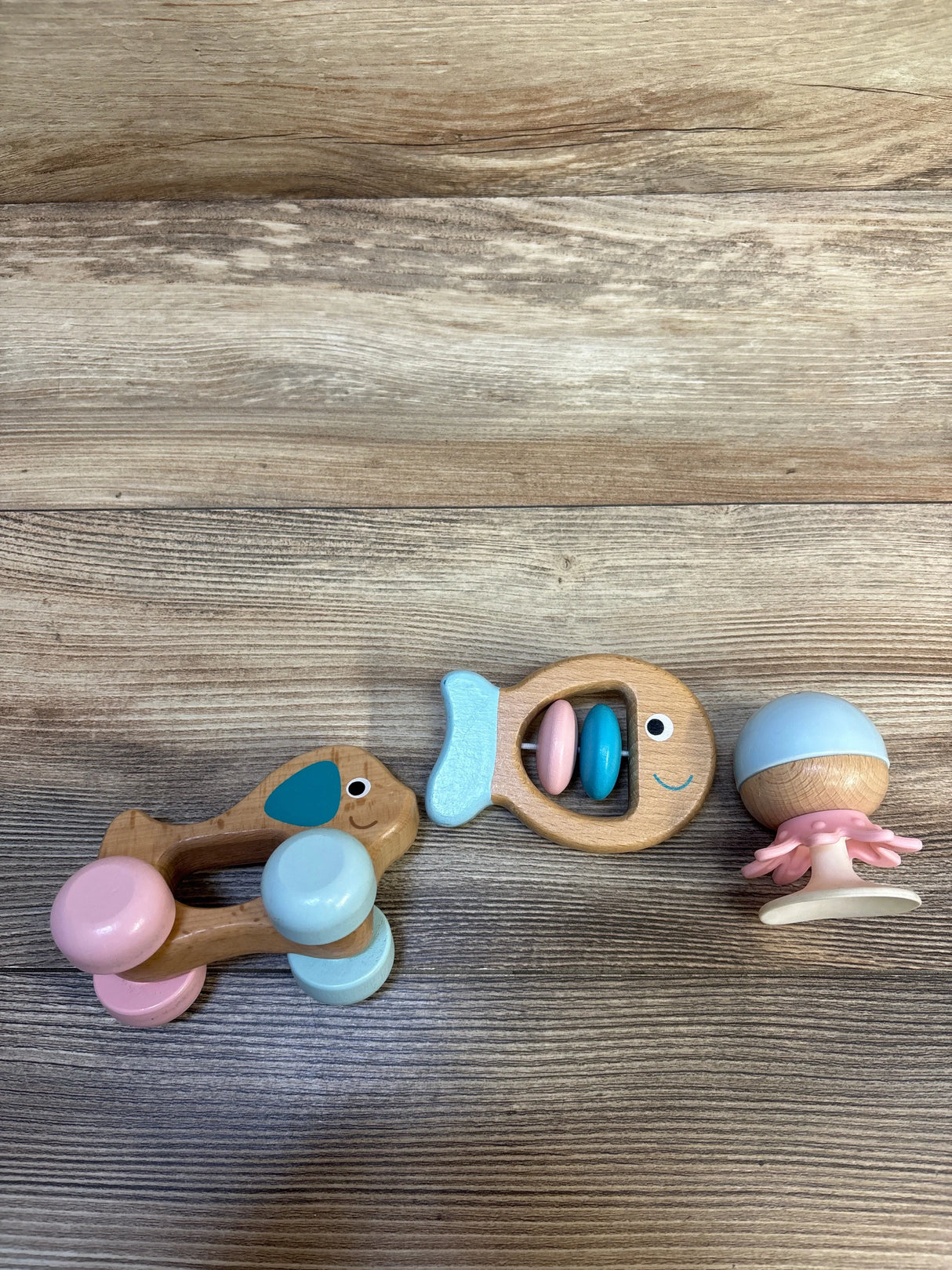 Wooden baby rattles and teether toys in pastel colors on wood background