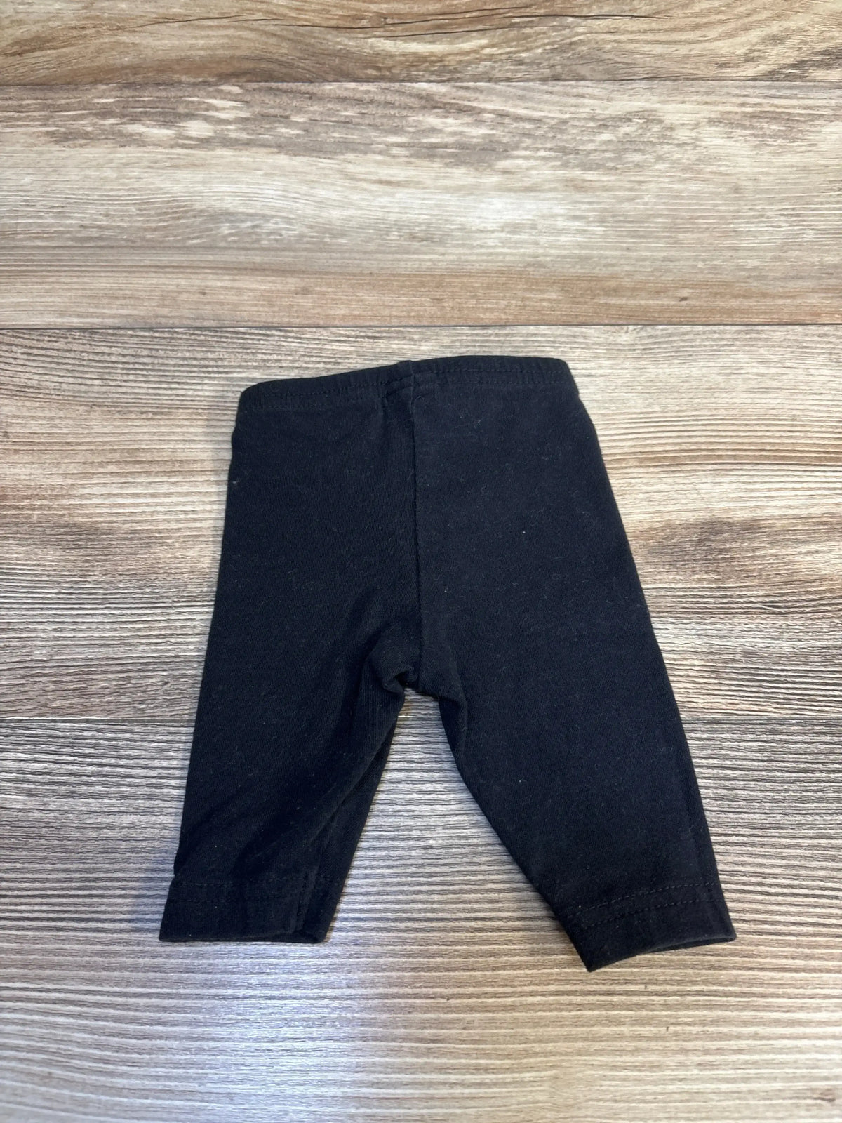 Black baby leggings on wood background, gently used kids clothing resale