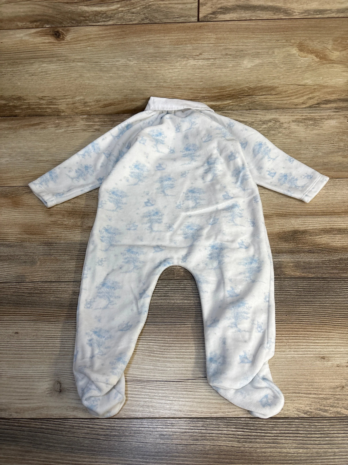 White baby footed sleeper with light blue cloud print on wood floor