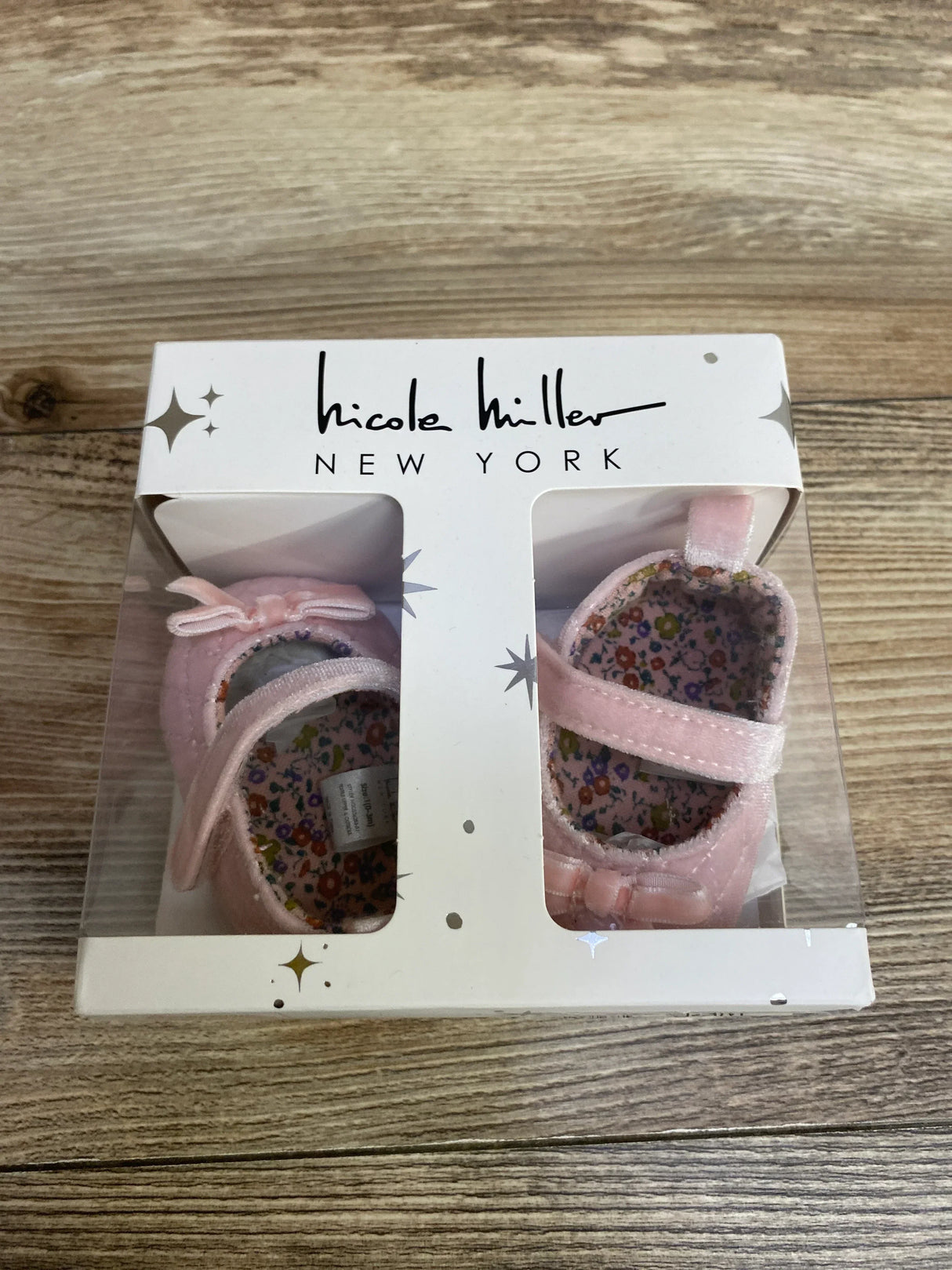 Pink baby girl shoes with floral lining in a gift box on wood surface