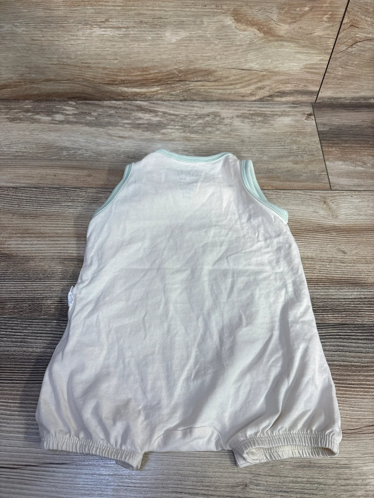 Back flat lay of cream Sinsay x Tiny Tatty Teddy tank romper with mint ribbed trim and elastic legs on wood floor