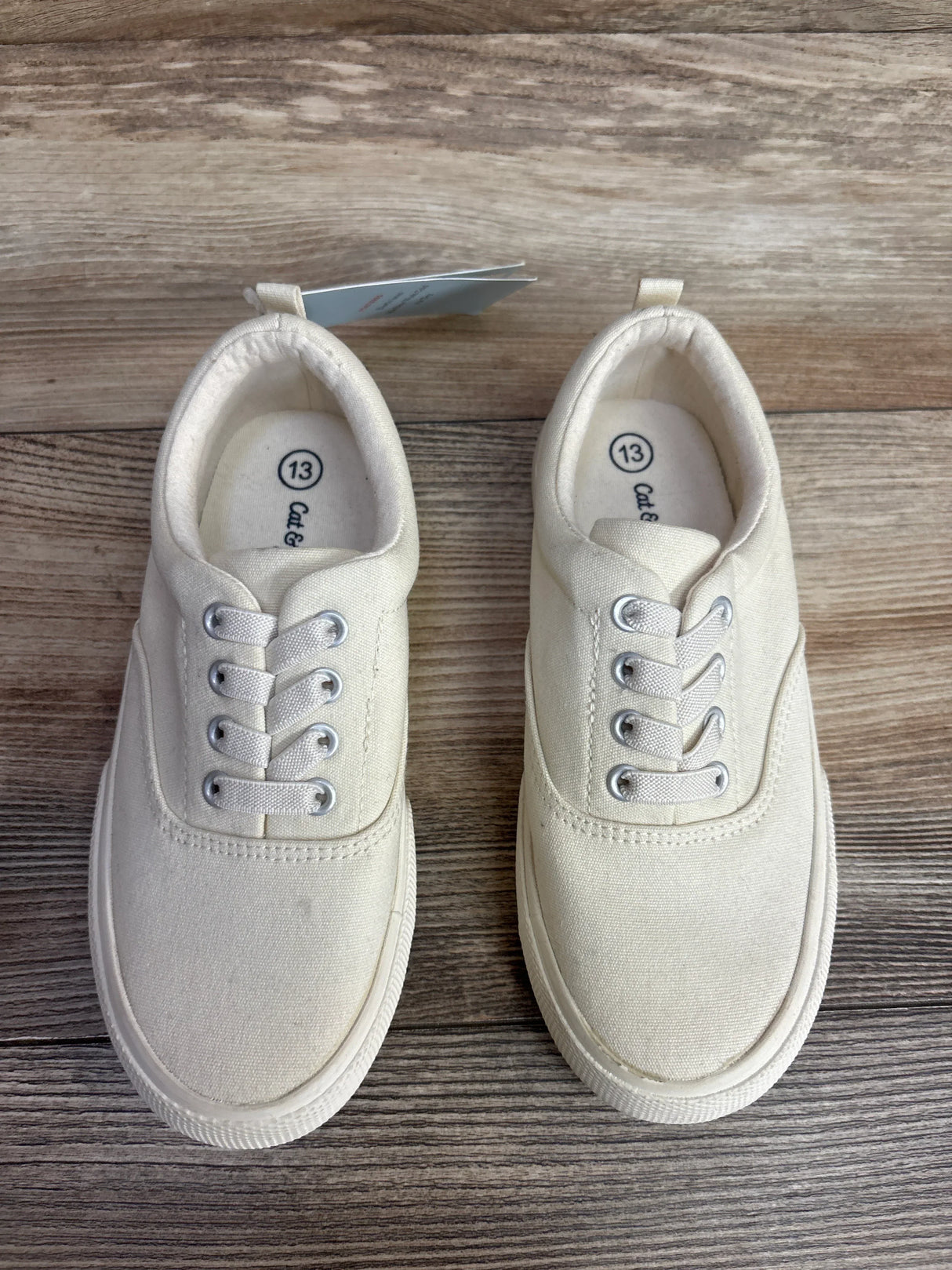 Pair of cream canvas kids' sneakers, size 13, on wood background, gently used shoes