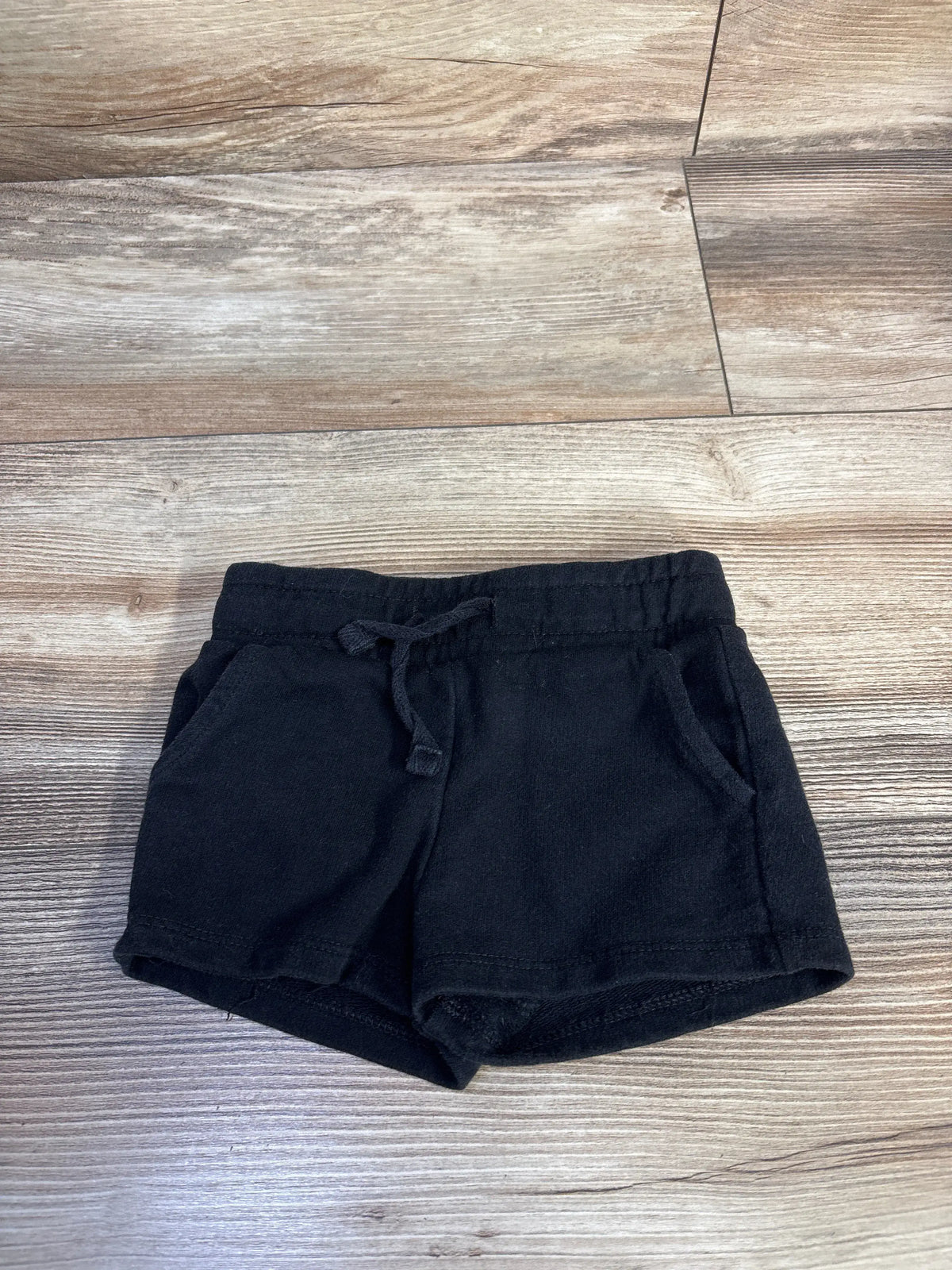 Cat & Jack black knit shorts for baby size 12m with drawstring waist on a wood background