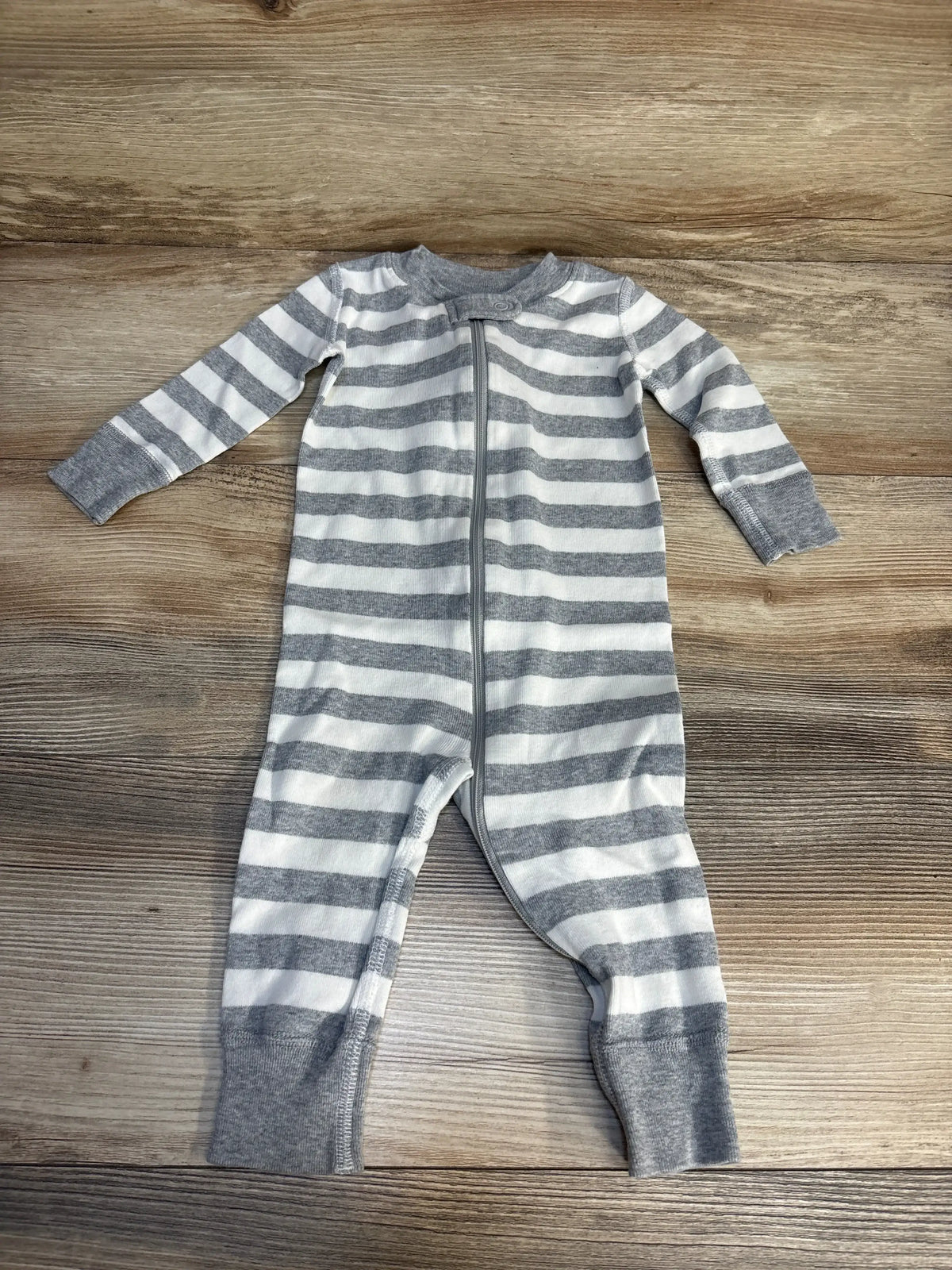 Gray and white striped baby sleeper with zipper, long sleeves, and cuffs on wood background