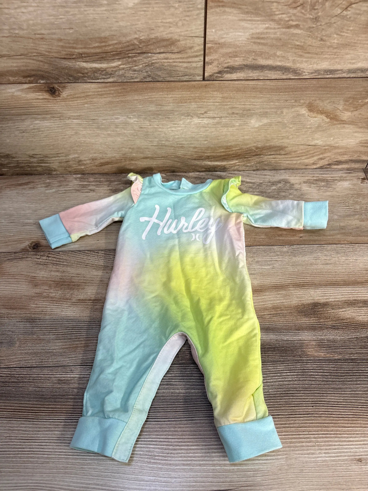 Flat lay girls Hurley coverall, pastel tie-dye blue and yellow, size 3m, front Hurley logo and ruffle shoulder on wood