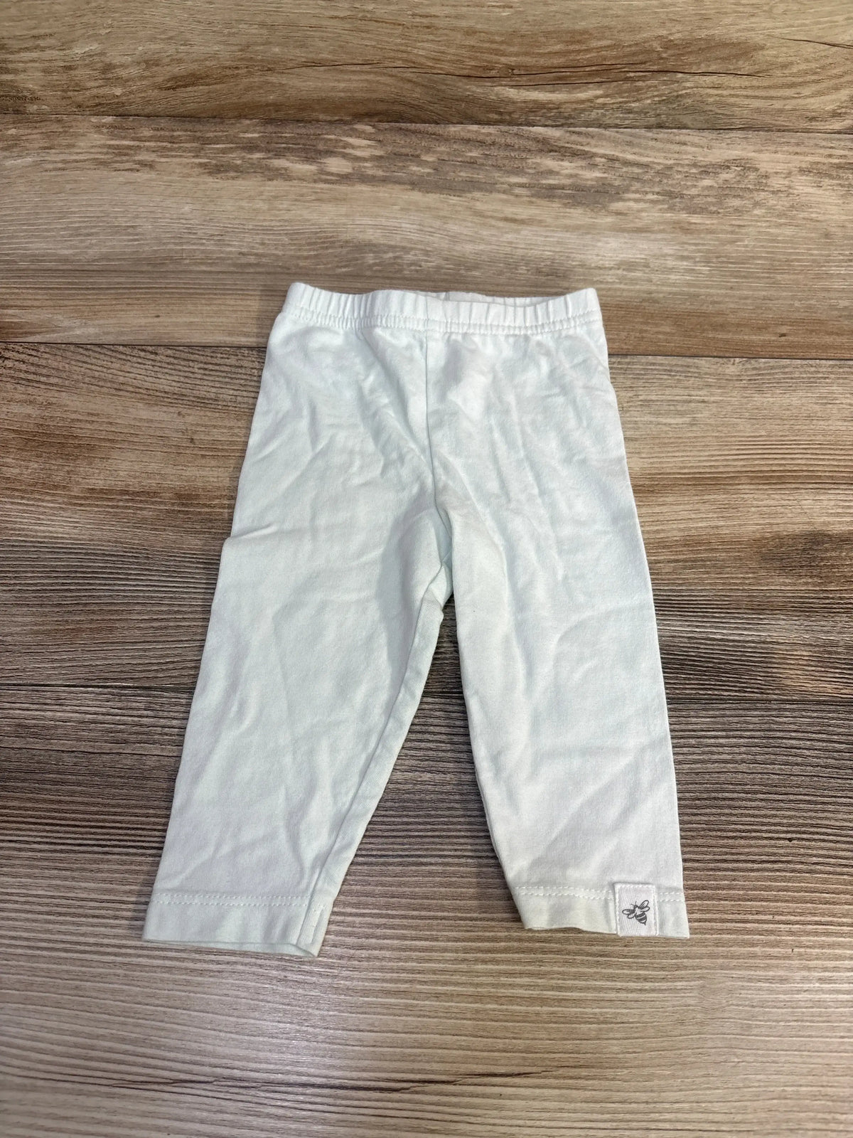 Front view of Burt’s Bees Baby pants in mint, size 0 to 3 months, with elastic waistband on wood background