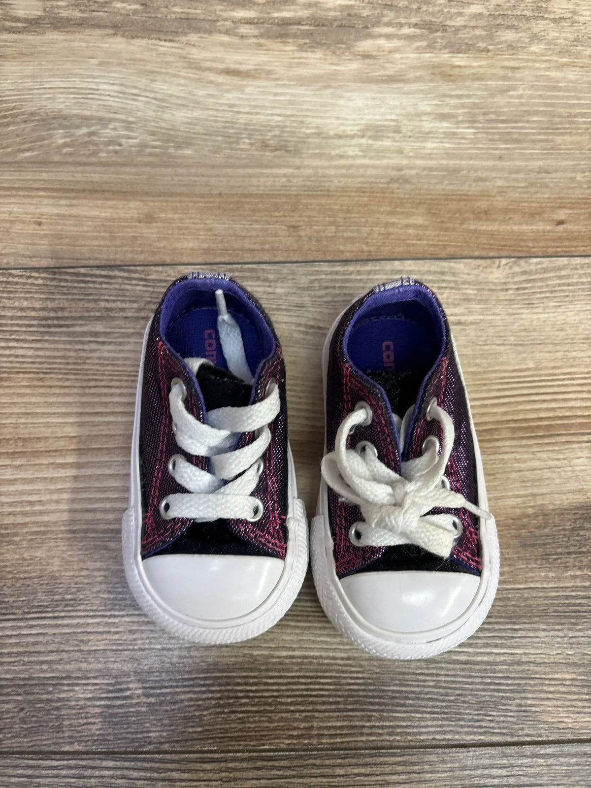 Top-down view of Converse Chuck Taylor All Star sneakers (3C), glittery purple with white toecaps and laces on wood floor