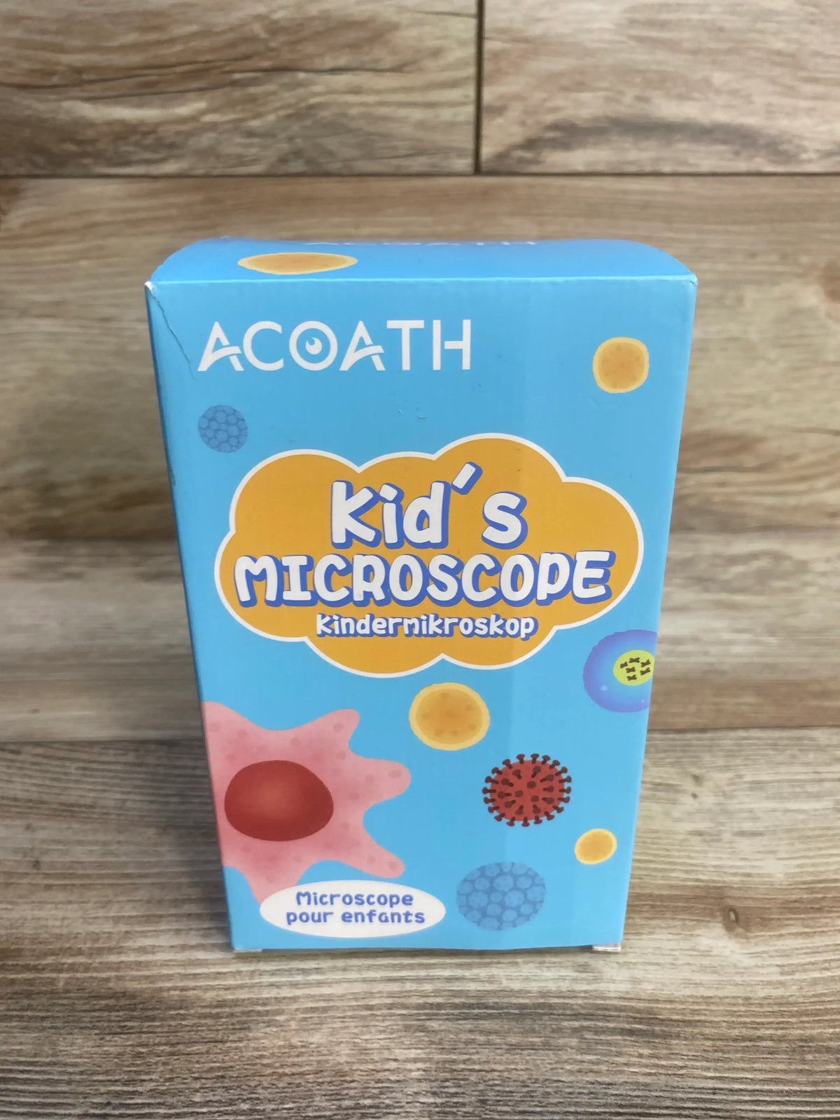 Front view of Acoath Kid’s Microscope box showing Kid’s Microscope headline, ACOATH logo and colorful cell illustrations on wood background