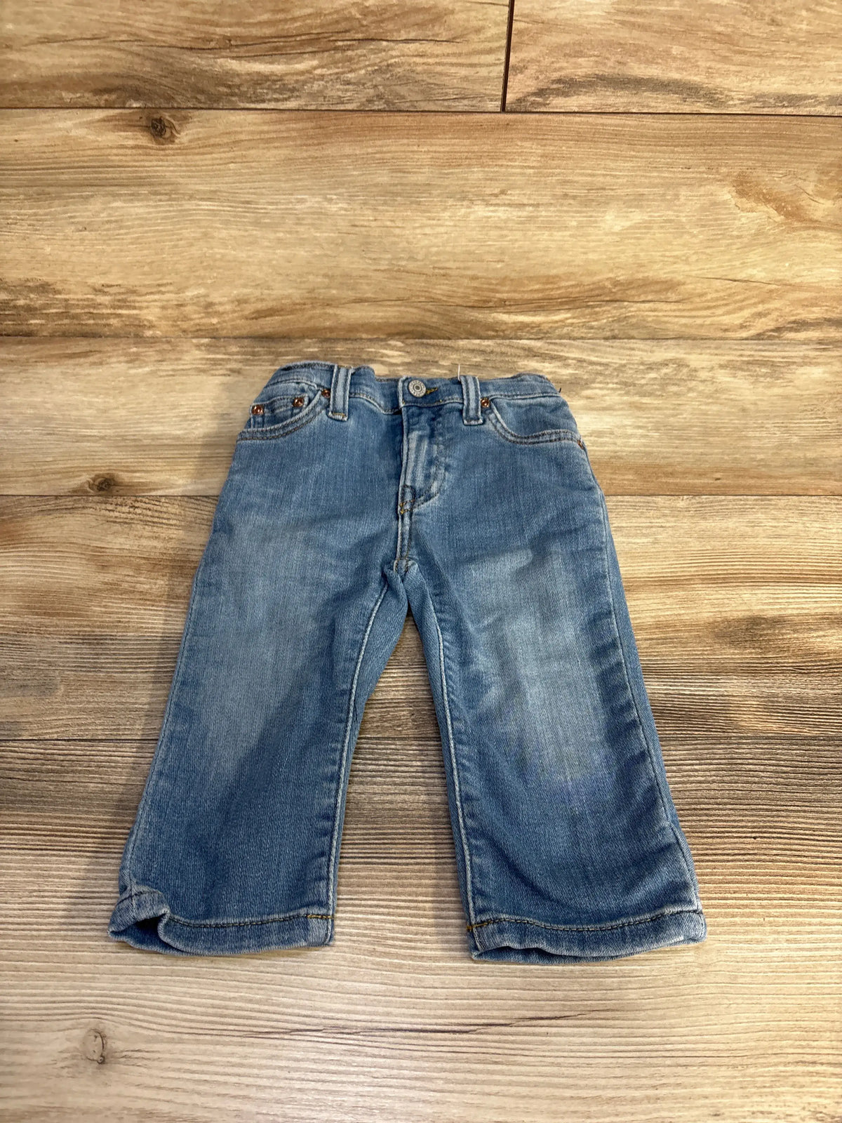 Front view of Polo Ralph Lauren Sullivan slim jeans showcasing blue denim and five-pocket styling with a wood background
