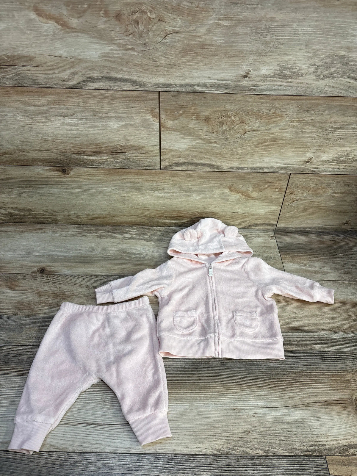 Top view of Carter’s 2-piece terry cloth hoodie and joggers set showcasing pink fabric and full-zip hoodie on a wood-look floor
