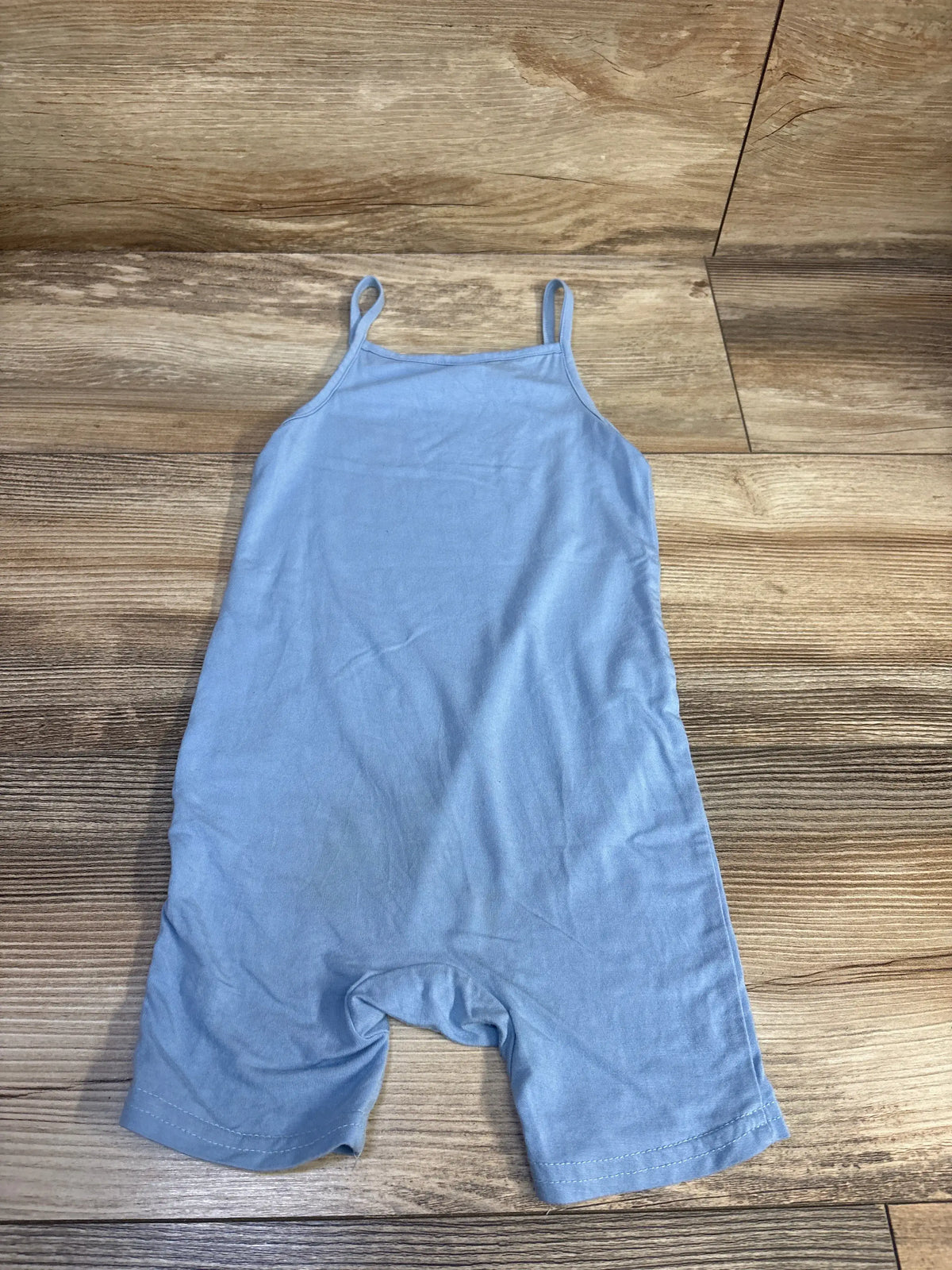 Front flat lay of blue toddler tank shortie romper showing spaghetti straps and short legs on wood background