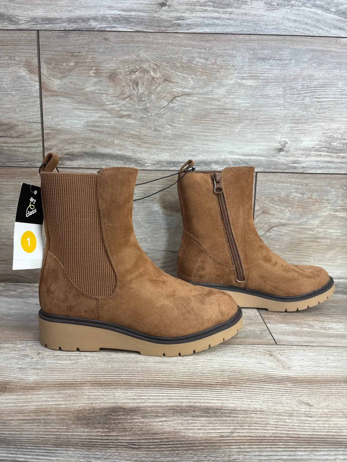 Brown kids suede ankle boots with side zipper and ribbed elastic panel on wood floor