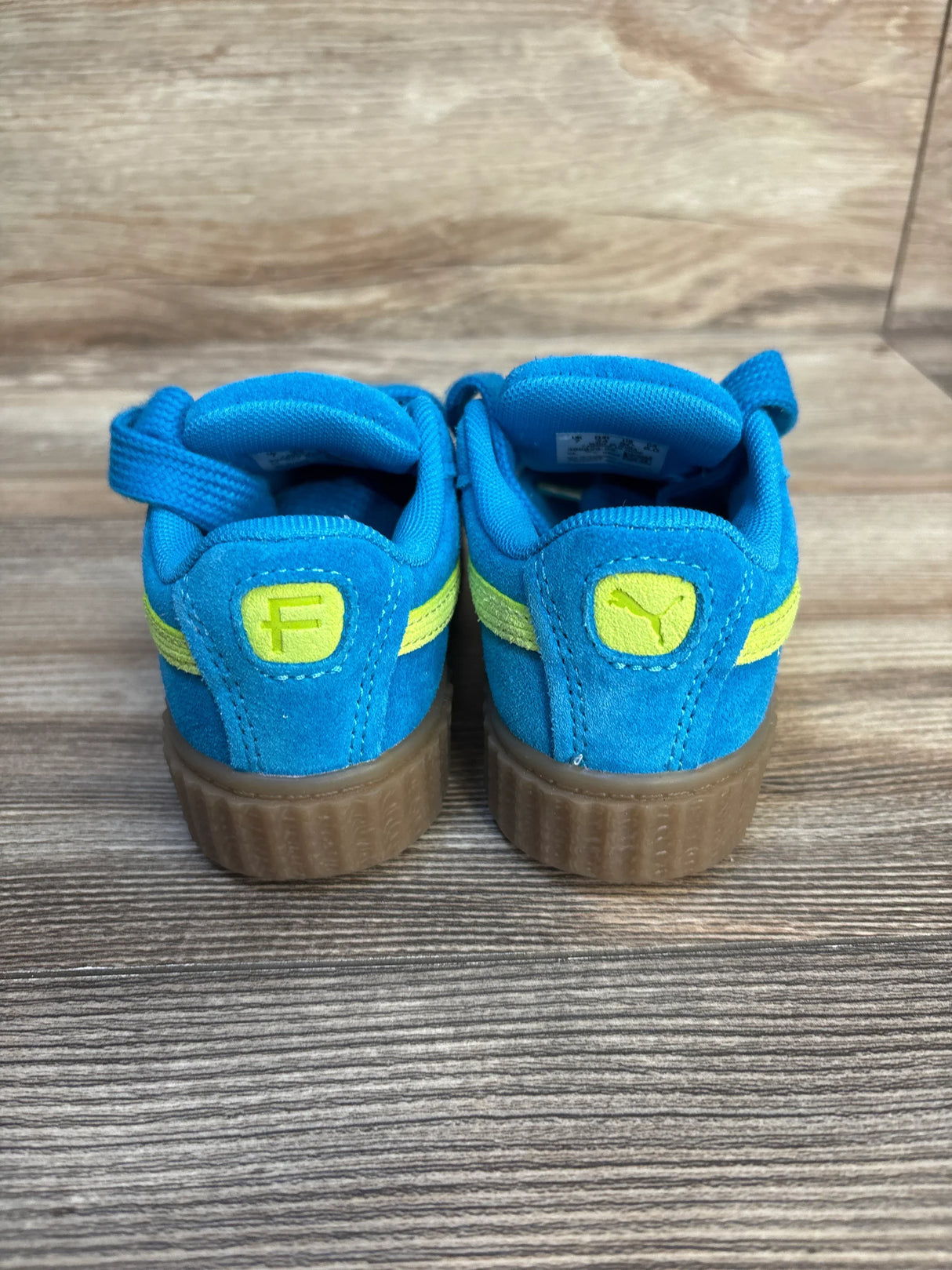 Back view of Puma x Fenty Creeper Phatty Sneakers sz 8c NWT showcasing blue suede upper with yellow Puma logo and gum sole on wood plank floor