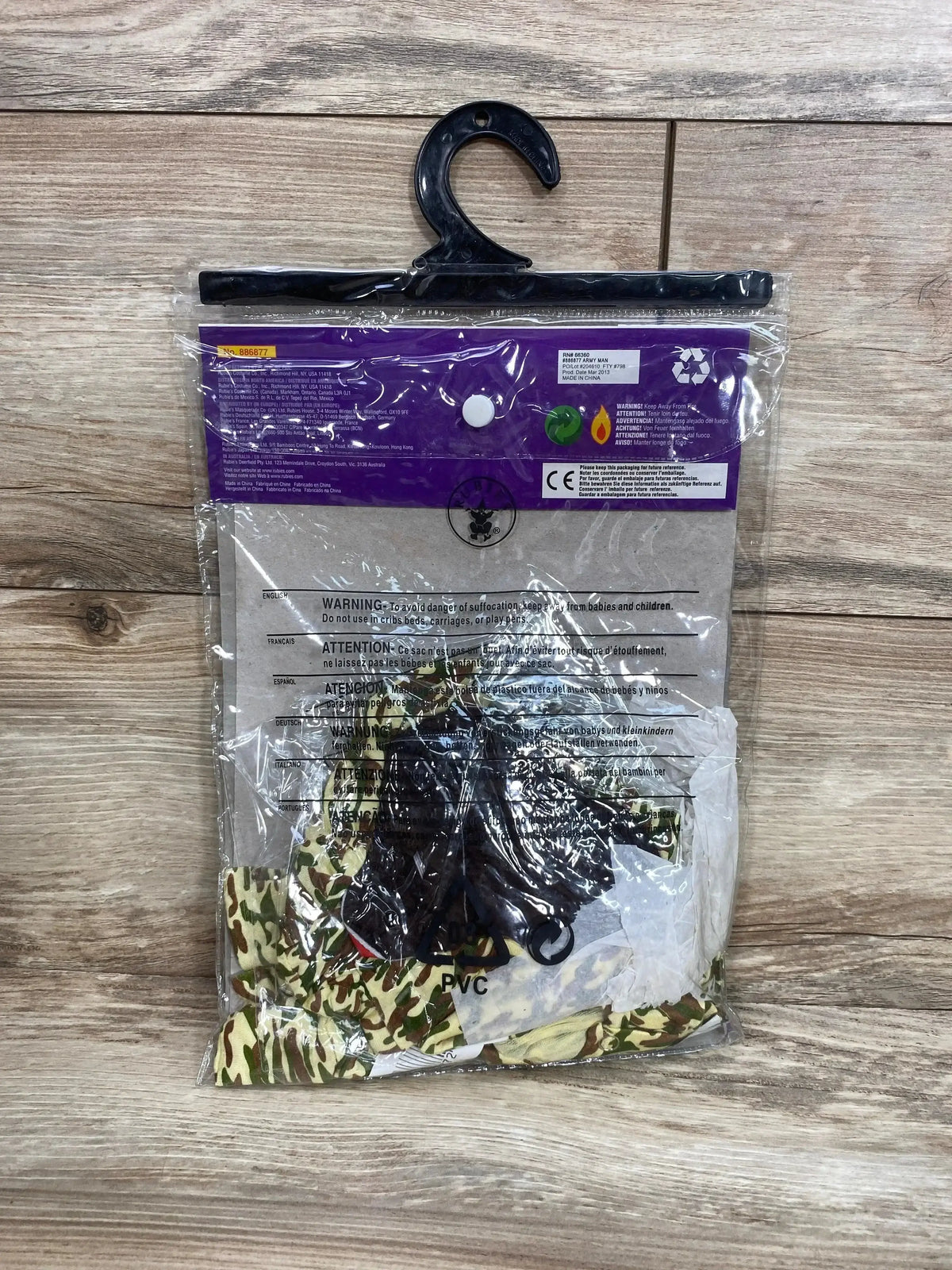 Front view of Rubie’s Babies 1st Halloween Army Man costume in camouflage with black accessories, packaged on a wood surface