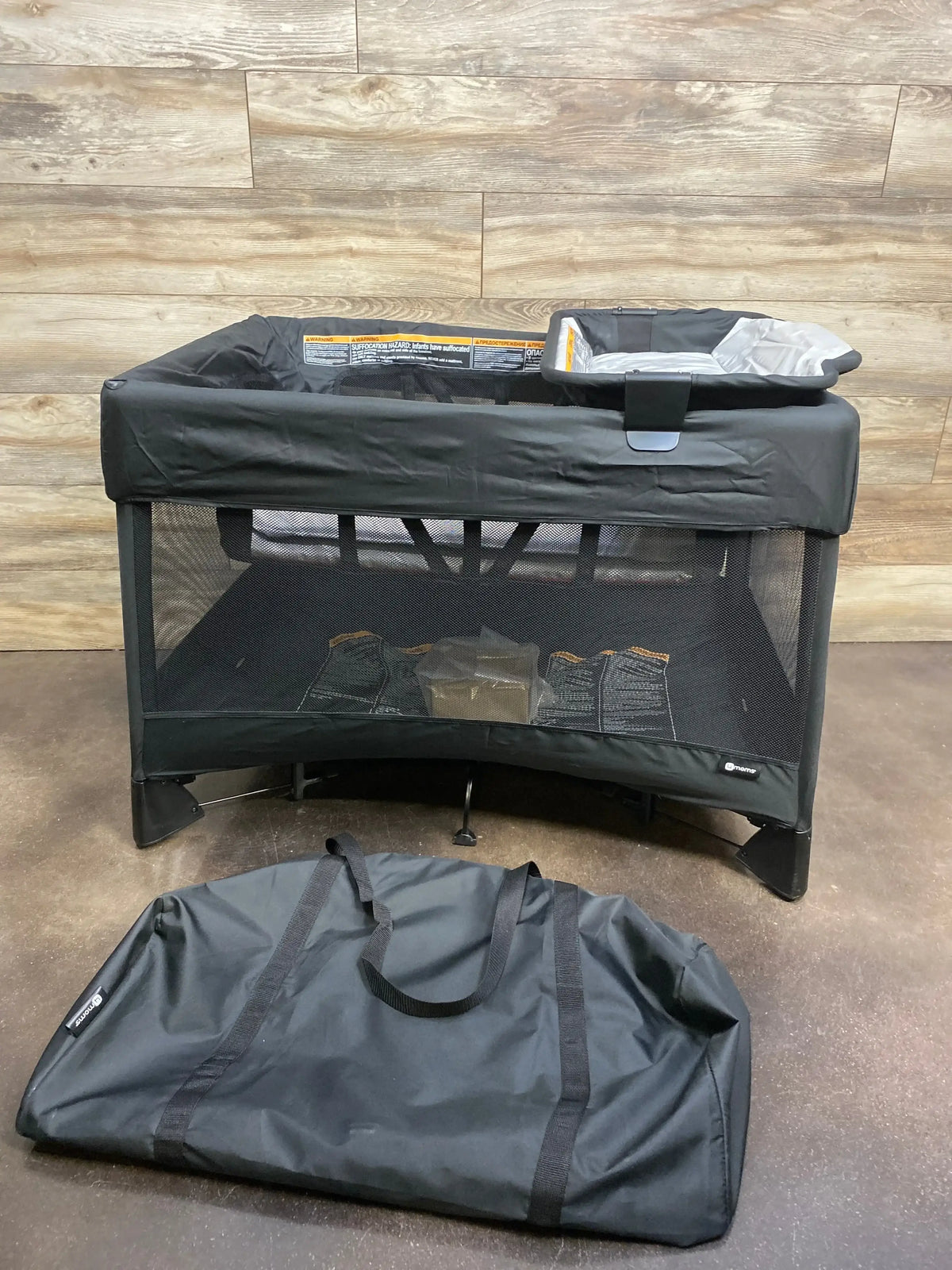 Front view of 4moms Breeze Plus playard in black with mesh sides, attached changer, and included carry bag