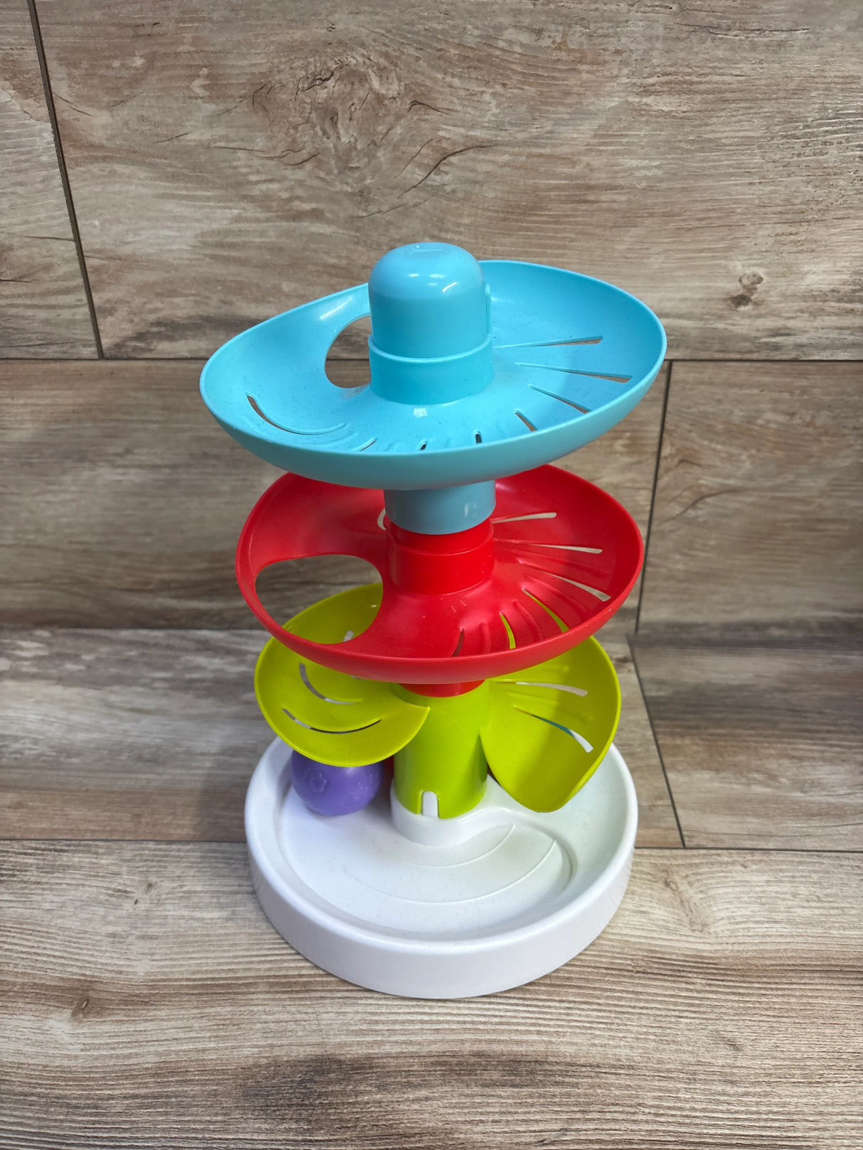 Front of Lollipop Spinning Ball Drop Tower with three spinning tiers, white base and purple ball on wood background