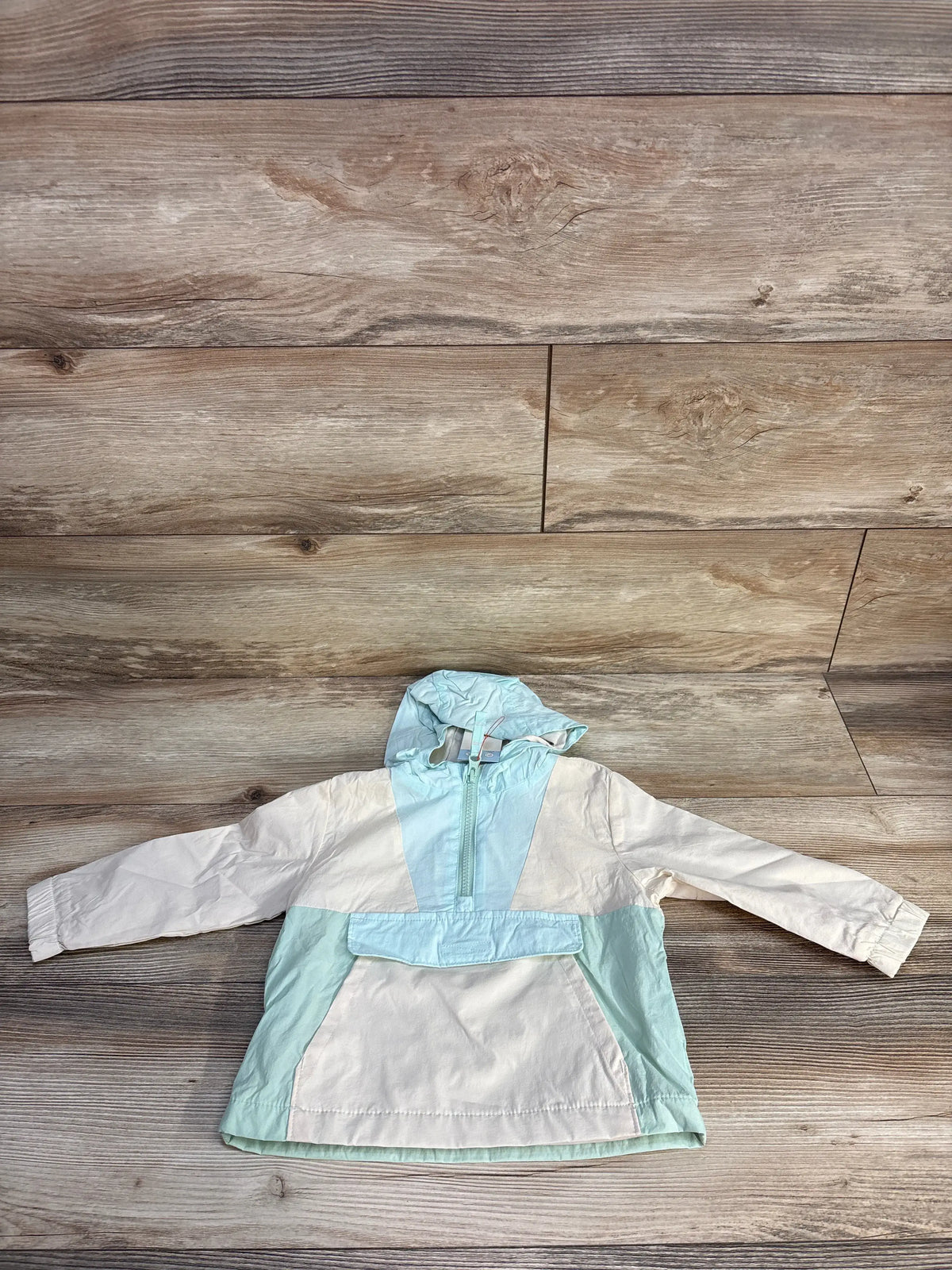 Front view of Cat & Jack colorblock hooded windbreaker in cream and aqua with hood, half zip, and pouch pocket