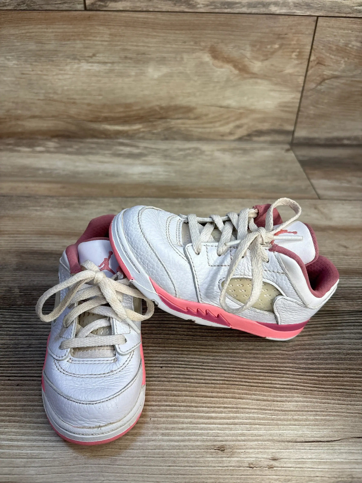 Top view of Air Jordan 5 Retro Low TD sneakers size 9C showing white leather uppers and pink midsoles on wood floor