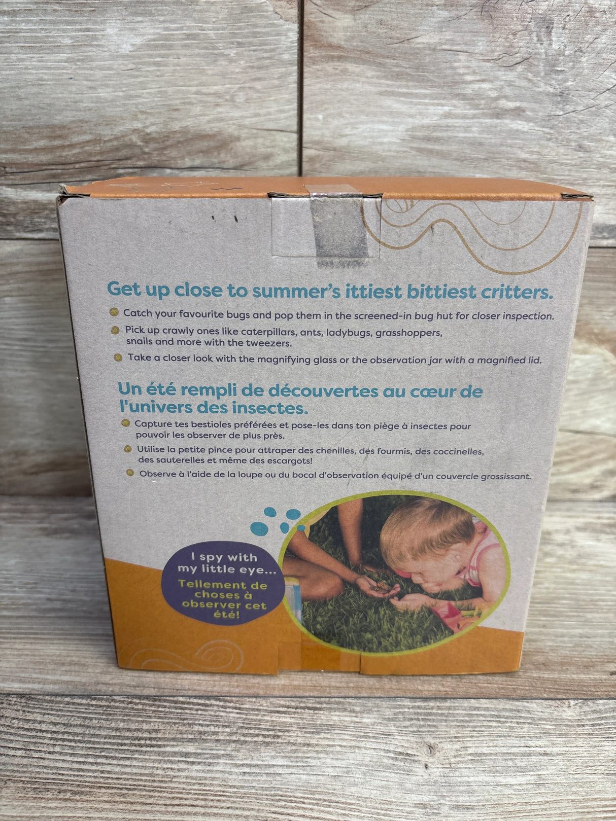 Bug exploration kit box with bilingual text and child observing insects on grass