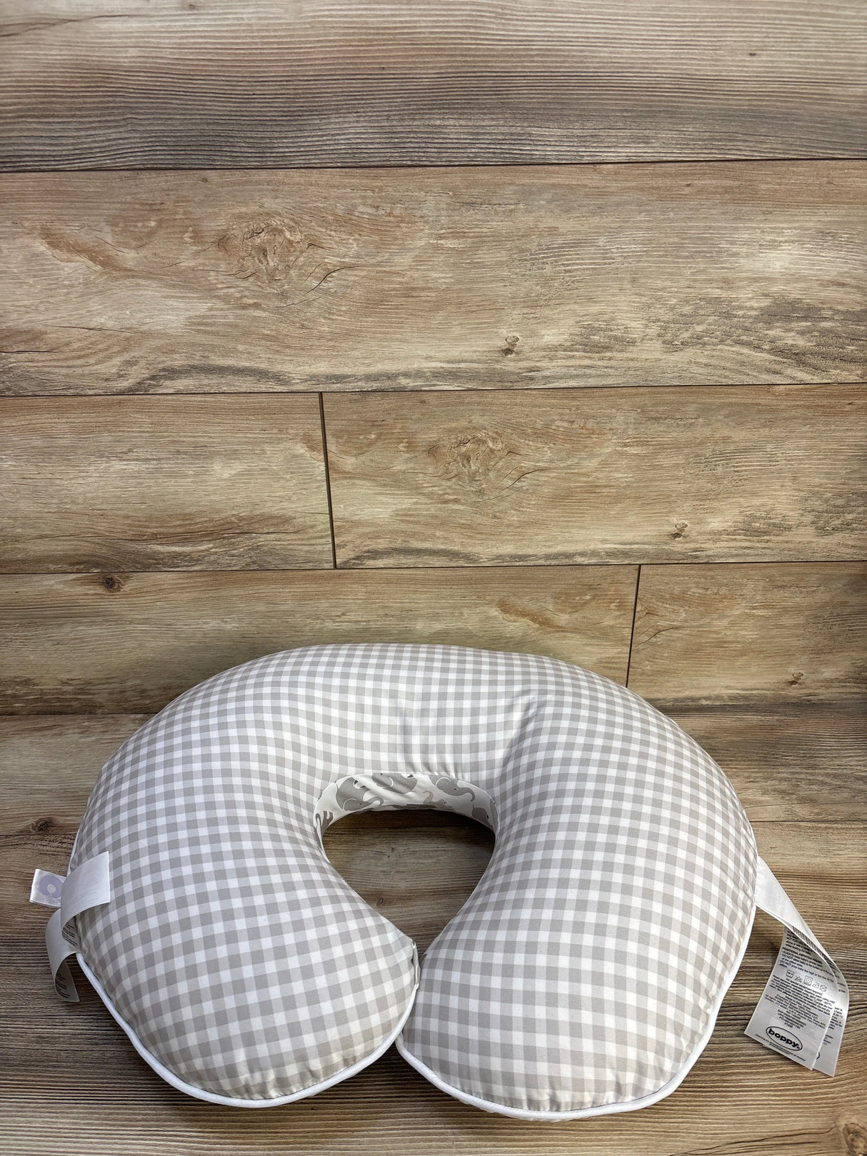 Top view of Boppy nursing pillow showing gray gingham slipcover and elephant-print inner lining on wood plank background