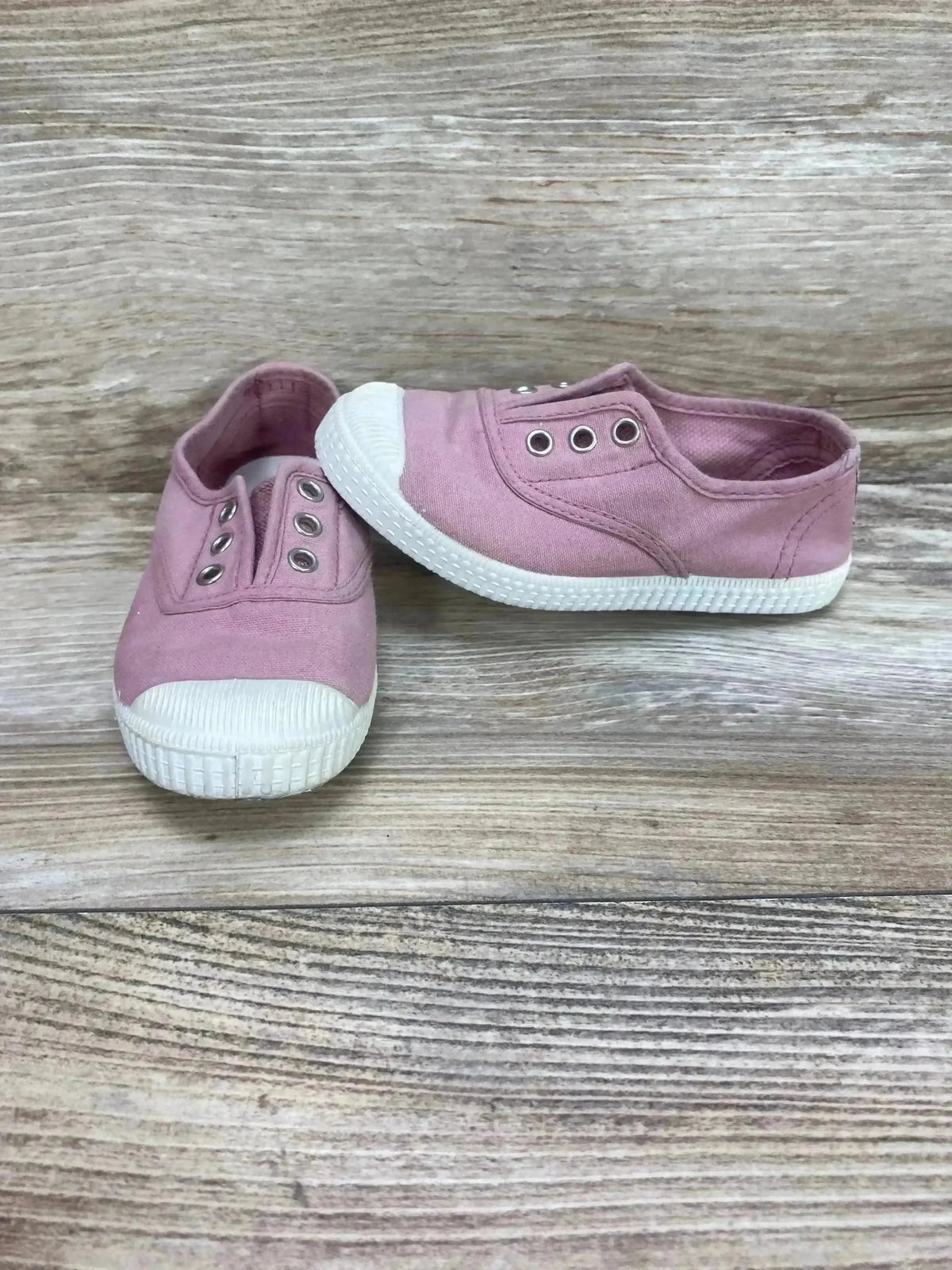 Front and side views of pink Cienta canvas slip-on sneakers, size 9C, with elastic openings and white rubber soles on wood