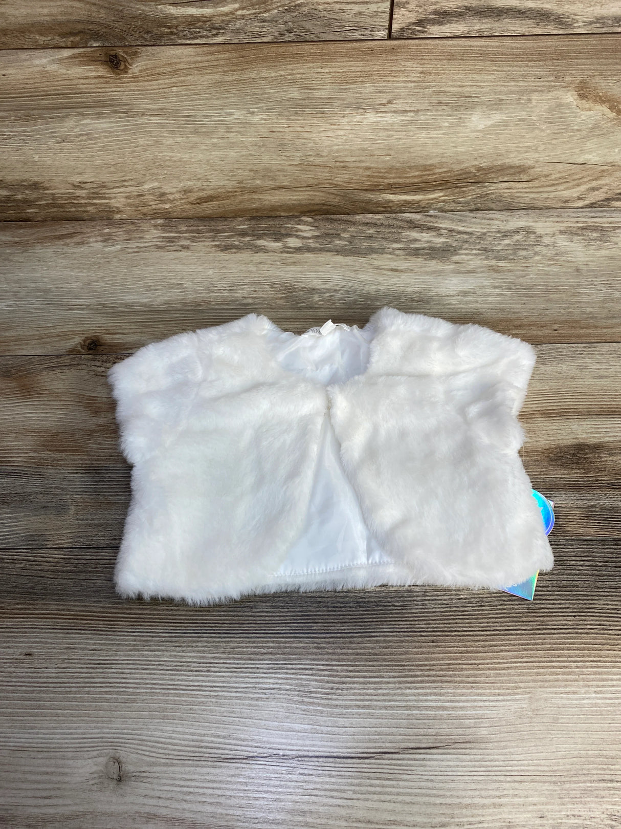 White faux fur vest for dolls on wooden background