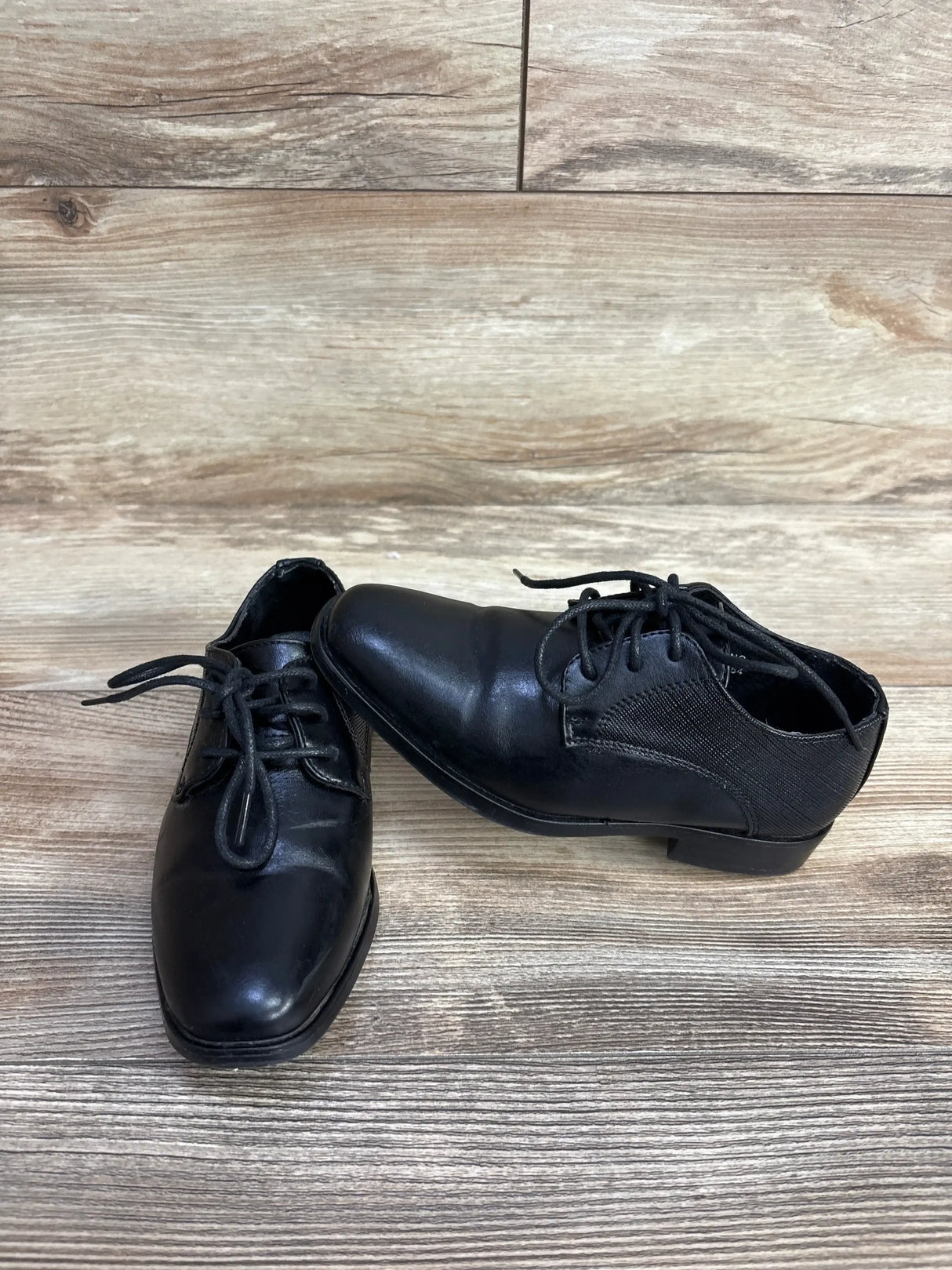 Three-quarter view of Bonafini Kids K-154 dress shoe showing lace-up front, elastic side panels, size 11C on wood floor