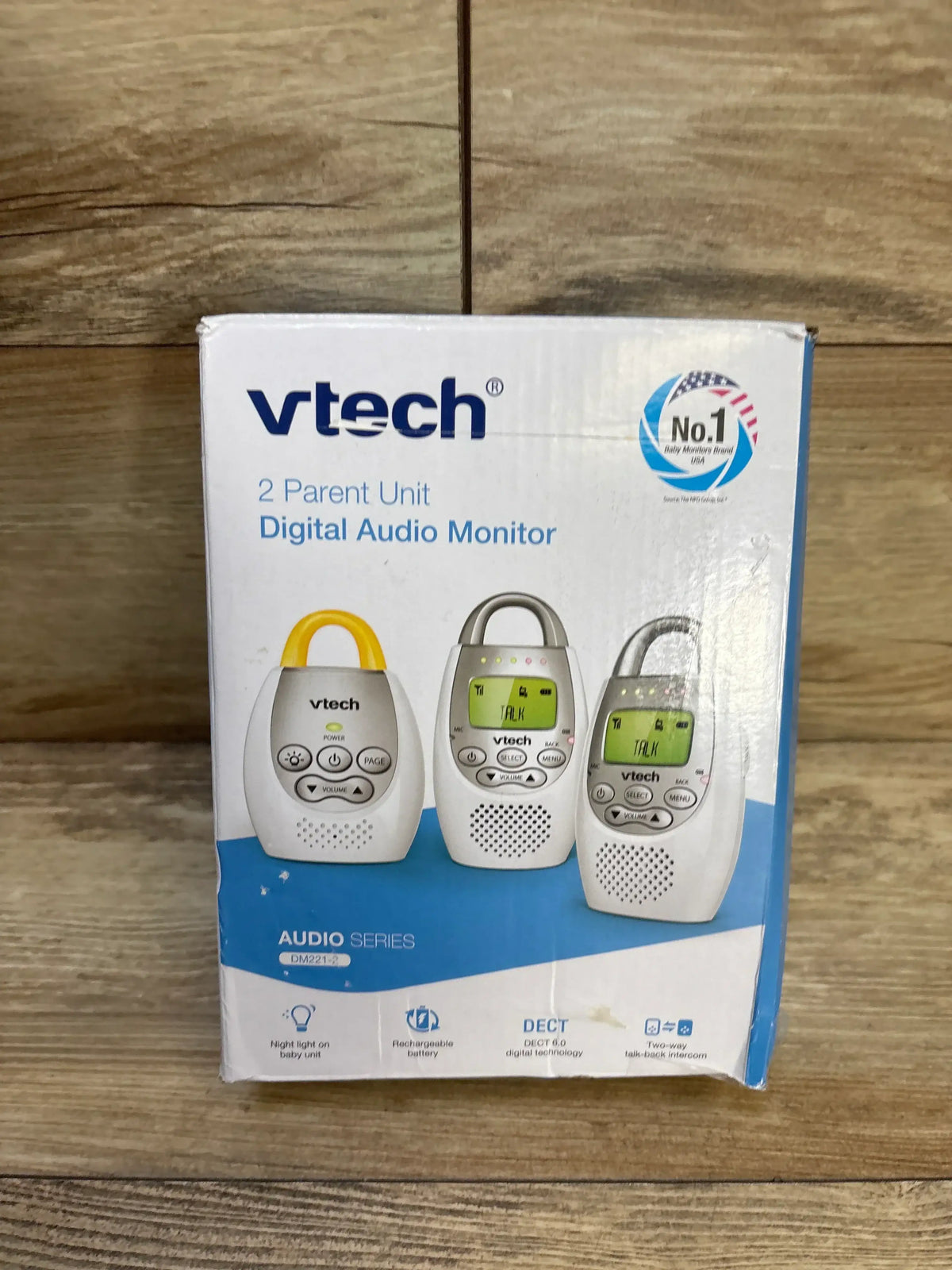 Front view of VTech DM221-2 digital audio monitor box showcasing two parent units and one baby unit with belt clip and LCD screens on wooden surface