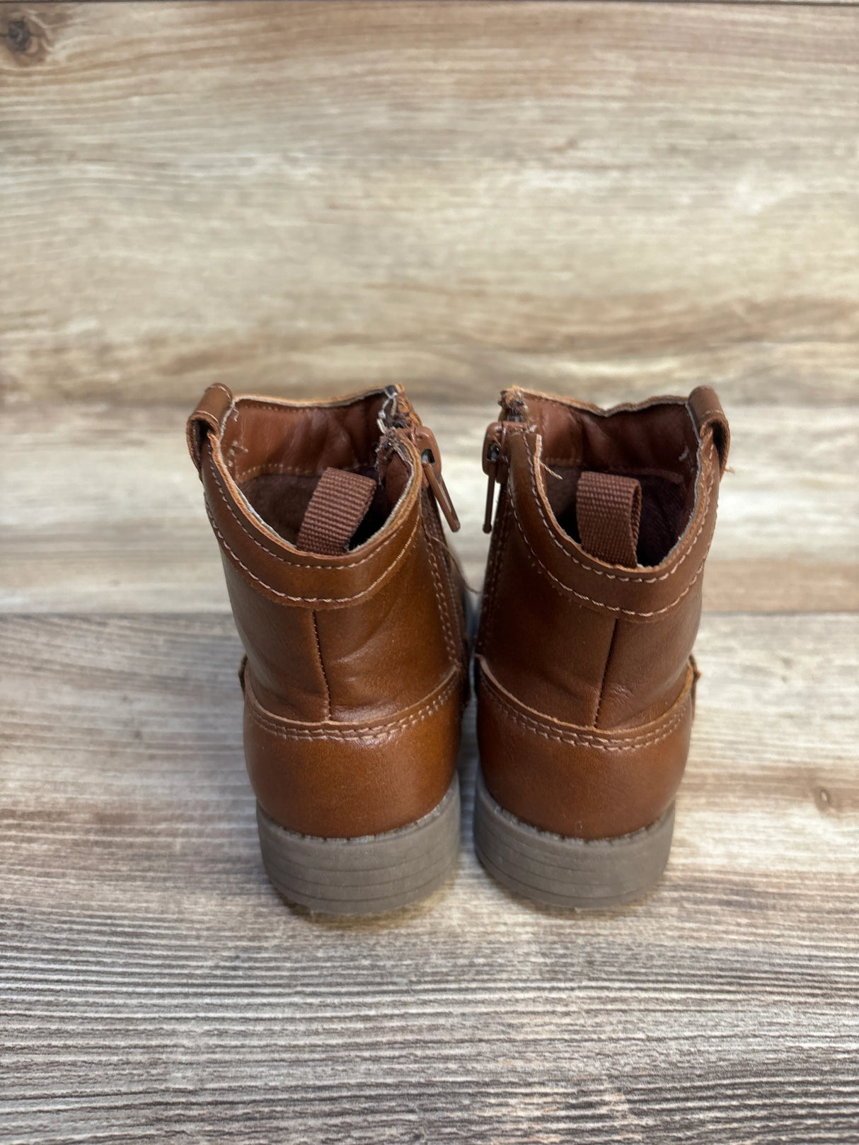 Back view of brown toddler boots with zippers on wood floor