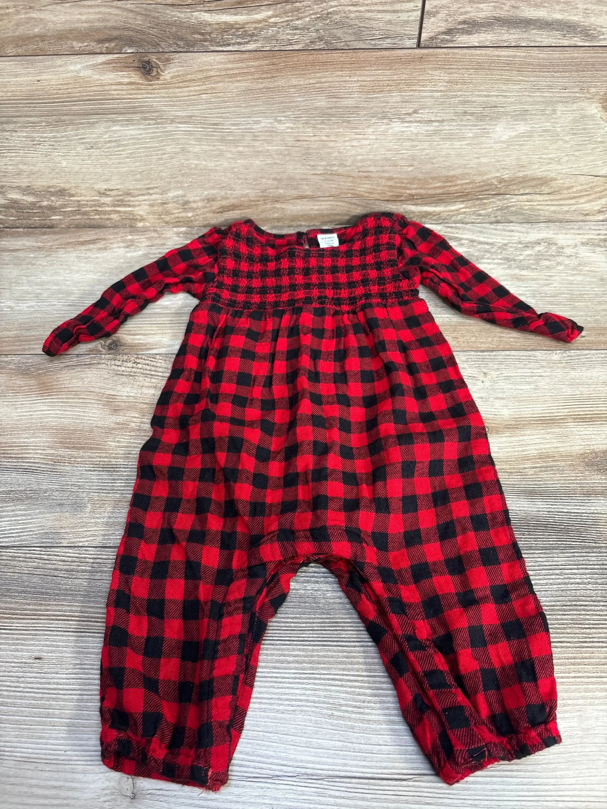 Red and black checkered long sleeve baby romper on wooden floor