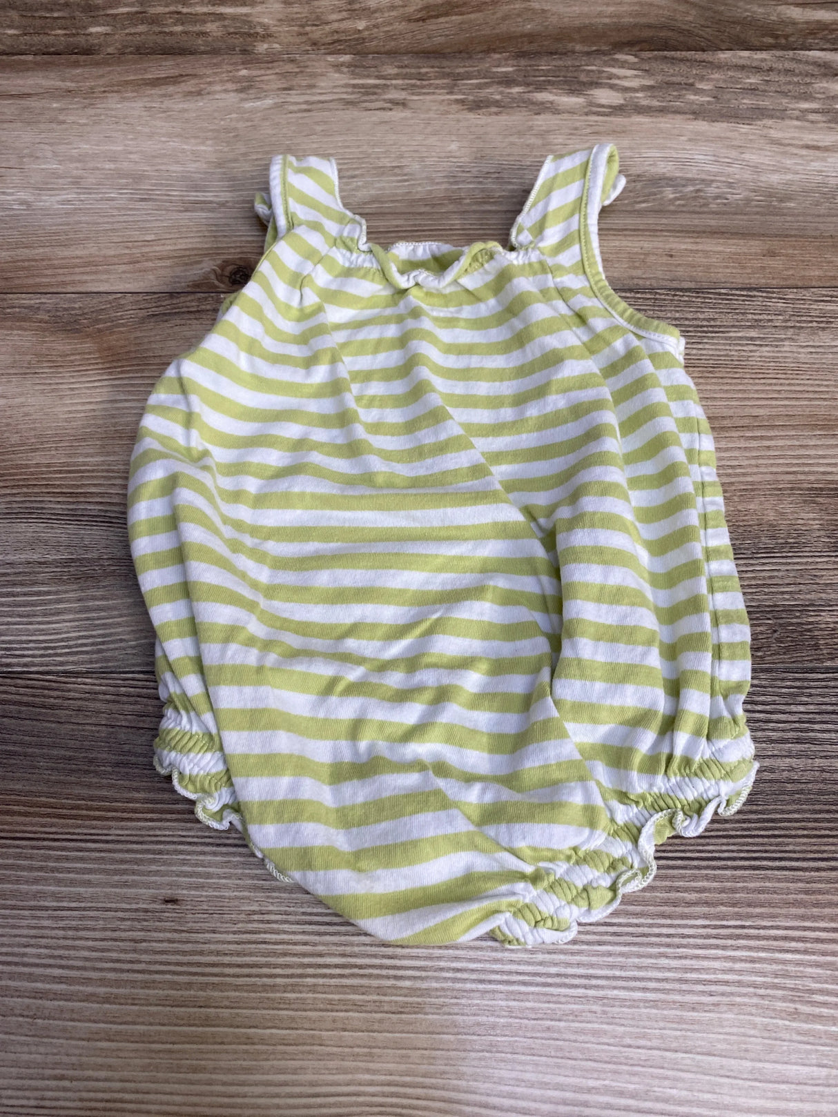 Flat lay of Old Navy green and white striped romper, ruffled shoulder straps and elastic leg openings on wood tabletop
