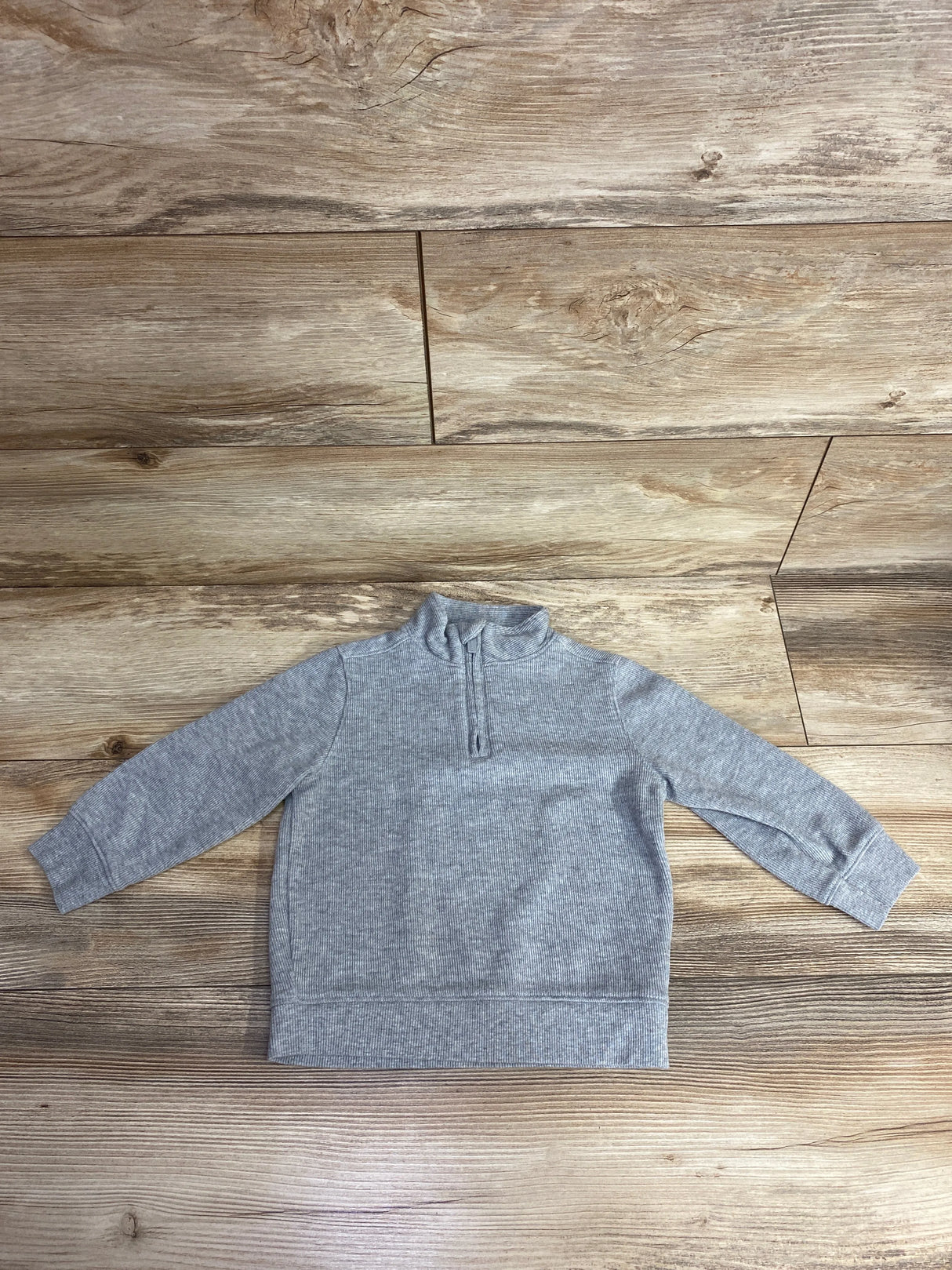 Gray long-sleeve toddler pullover with zip collar on wooden floor, kids clothing