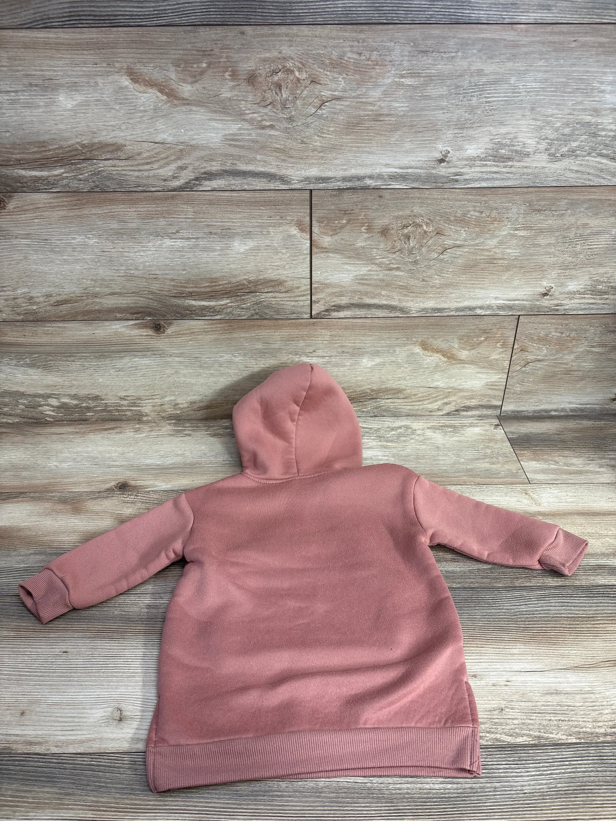 Pink toddler hooded sweatshirt laid flat on wood floor, children's clothing resale