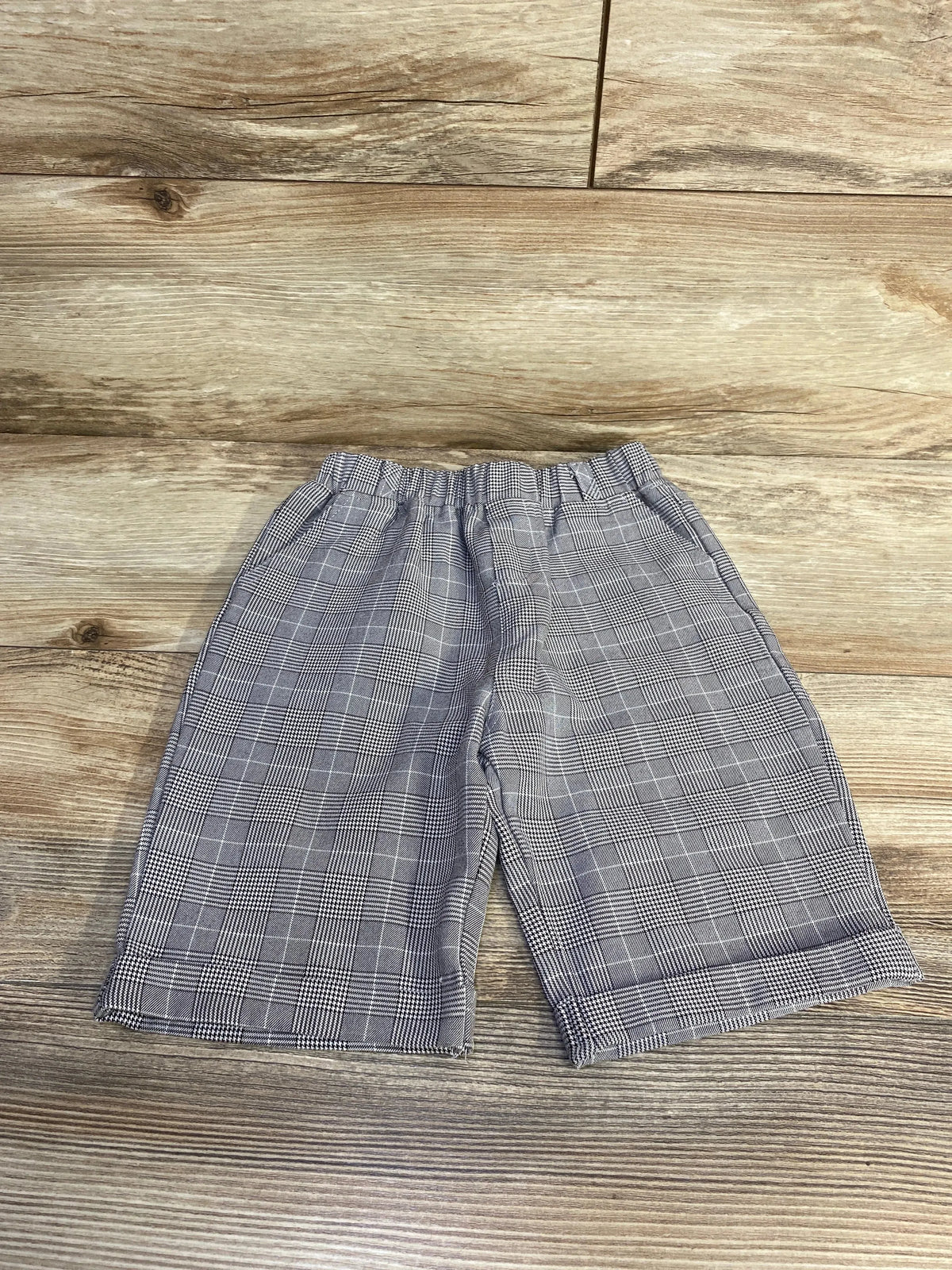 Front view of grey plaid toddler pull-on shorts with elastic waistband and cuffed hems on wooden floor