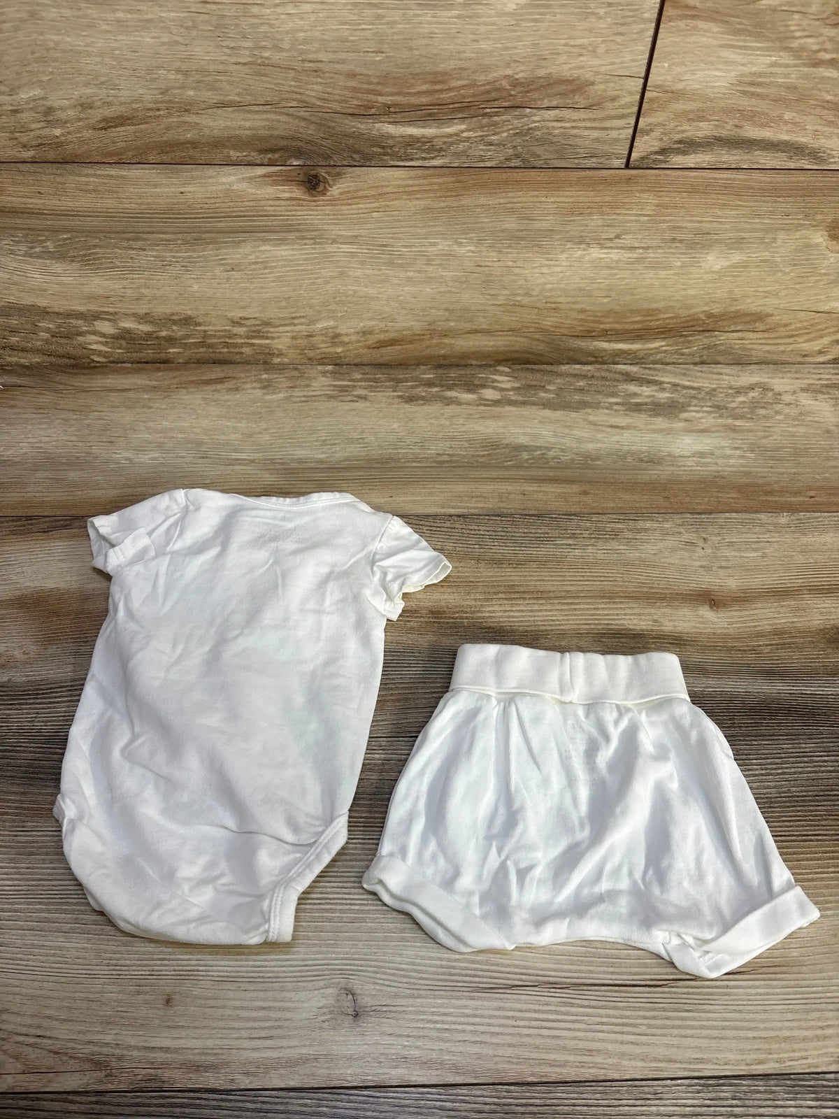 Flat lay of white kimono bodysuit and foldover shorts set, 3M, foldover waist on light wood background