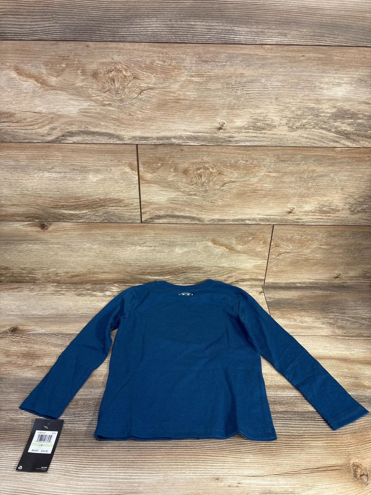 Back view of Under Armour long-sleeve toddler shirt, blue 4T, showing small logo at upper back on wood background