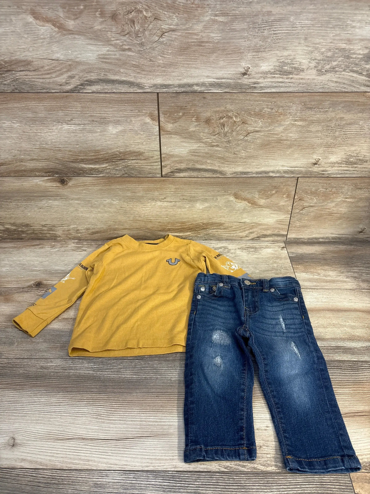 Yellow long sleeve kids shirt with blue distressed jeans, kids clothing set on wood floor