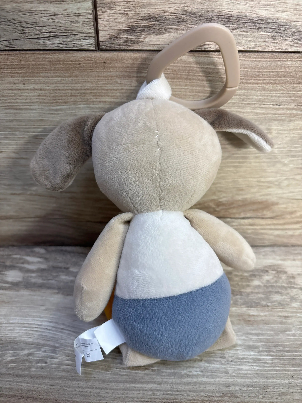 Rear view of DreamGro Stroller Plush Dog Toy showcasing its stroller attachment loop and soft plush body on a wood-grain surface