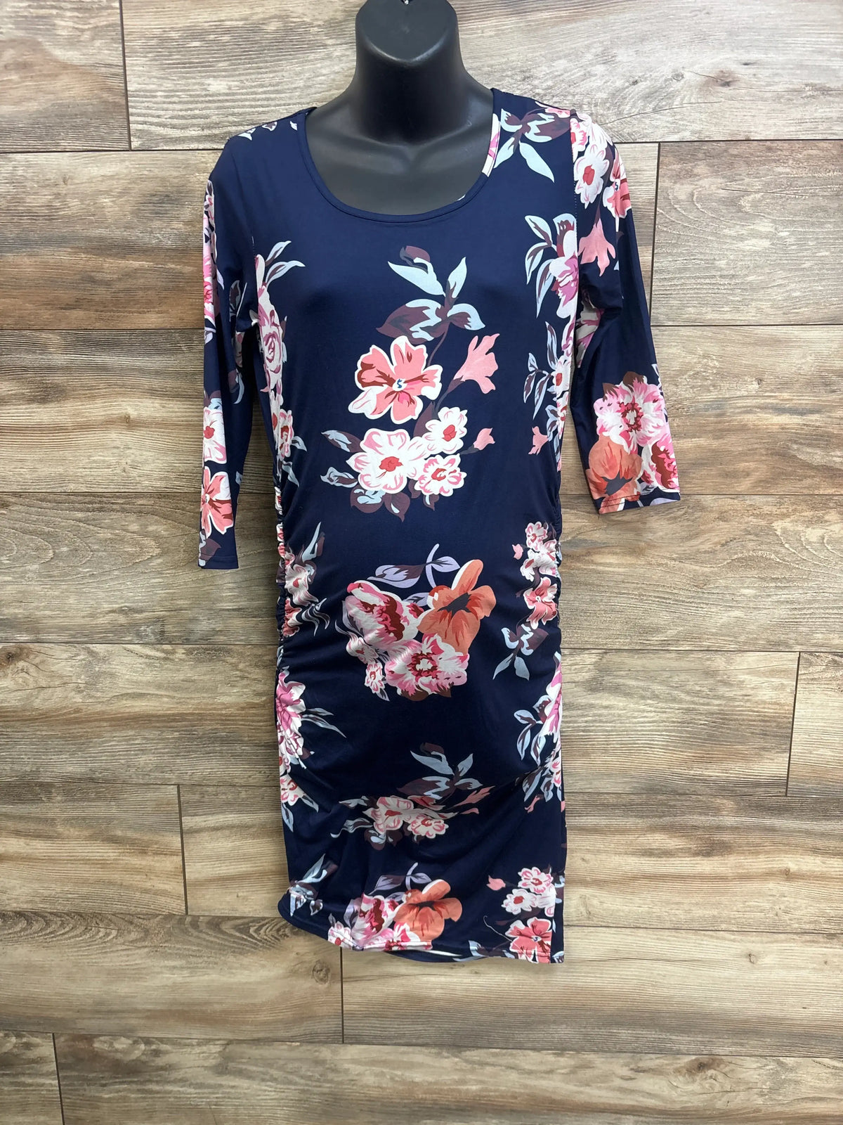 Front view of Miss Qee navy maternity floral bodycon dress showcasing floral print on a black mannequin over wood flooring