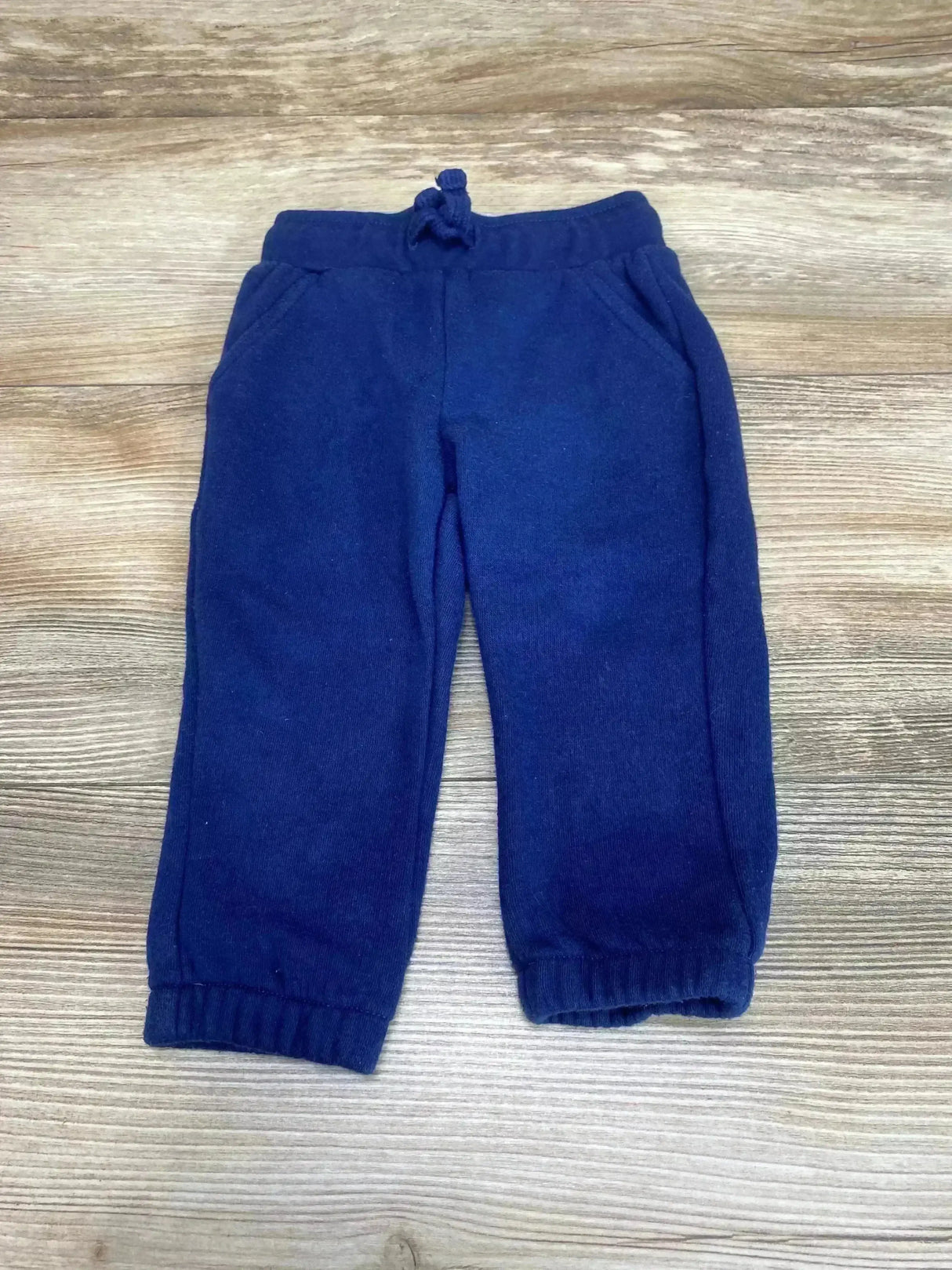 Top down view of navy Okie Dokie drawstring joggers 9M with elastic cuffs and front pockets on light wood background